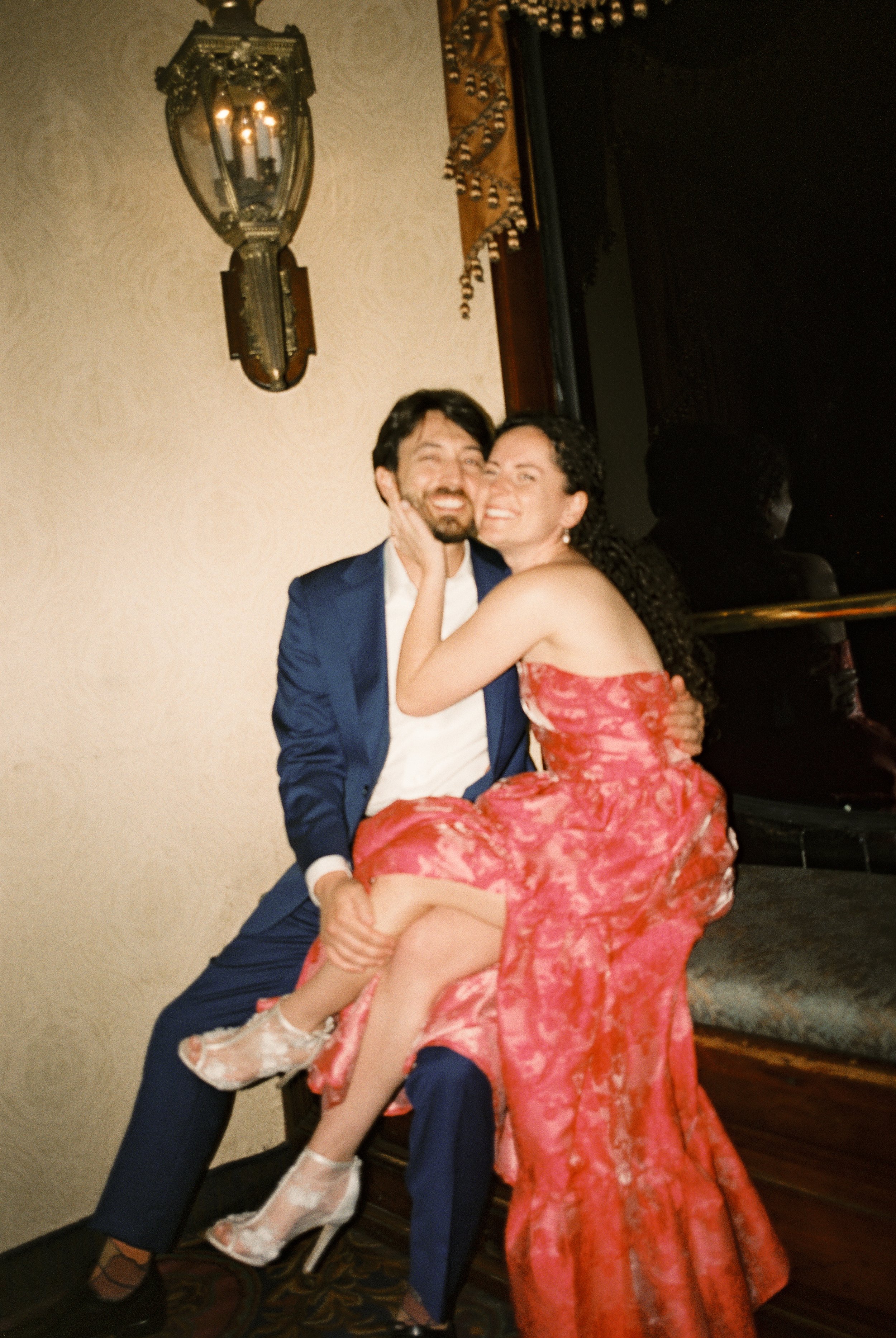 Couple laughing together in formal attire during their wedding rehearsal dinner.