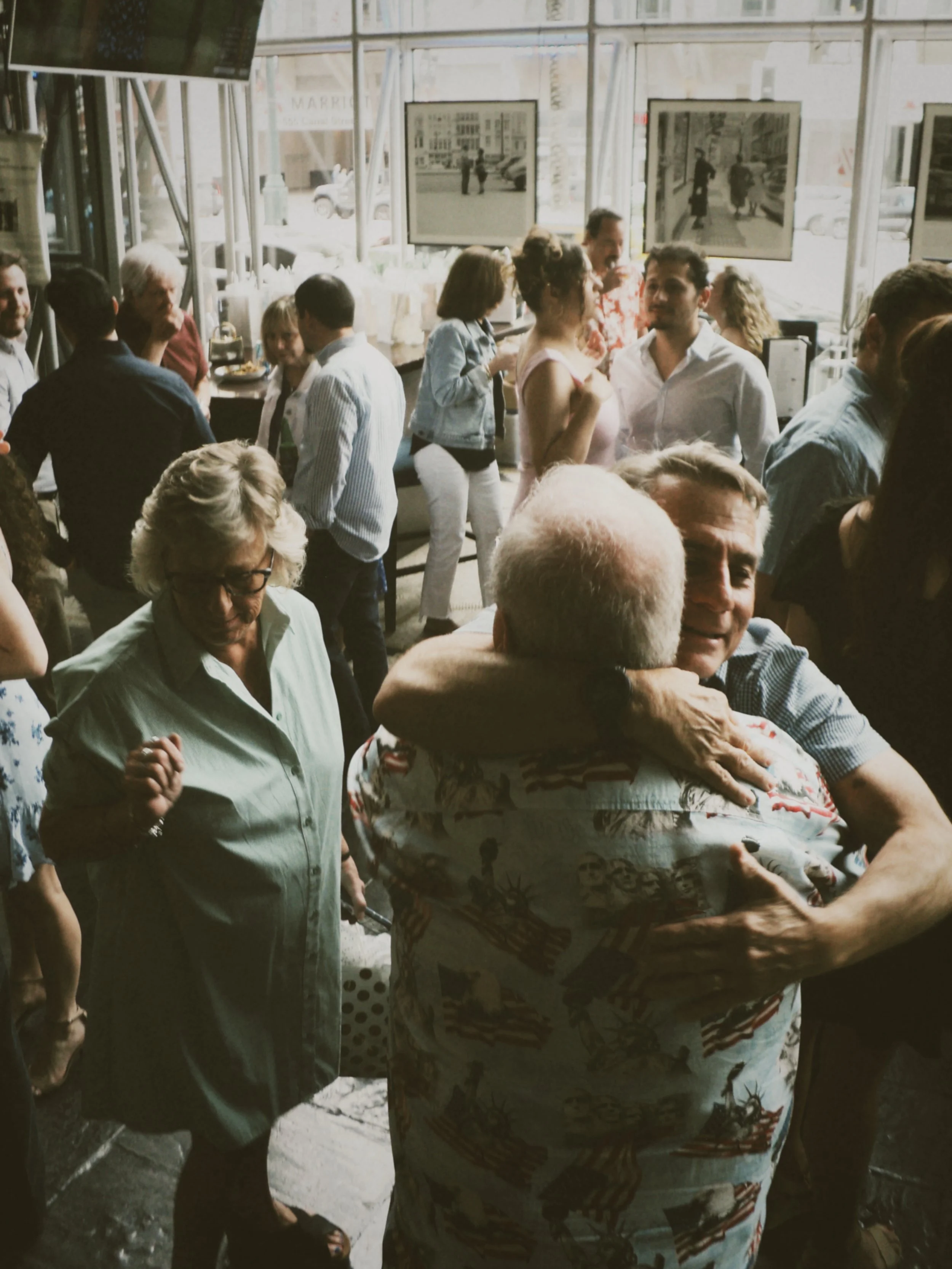 Guests greeting each other with hugs while mingling at a lively rehearsal dinner reception.