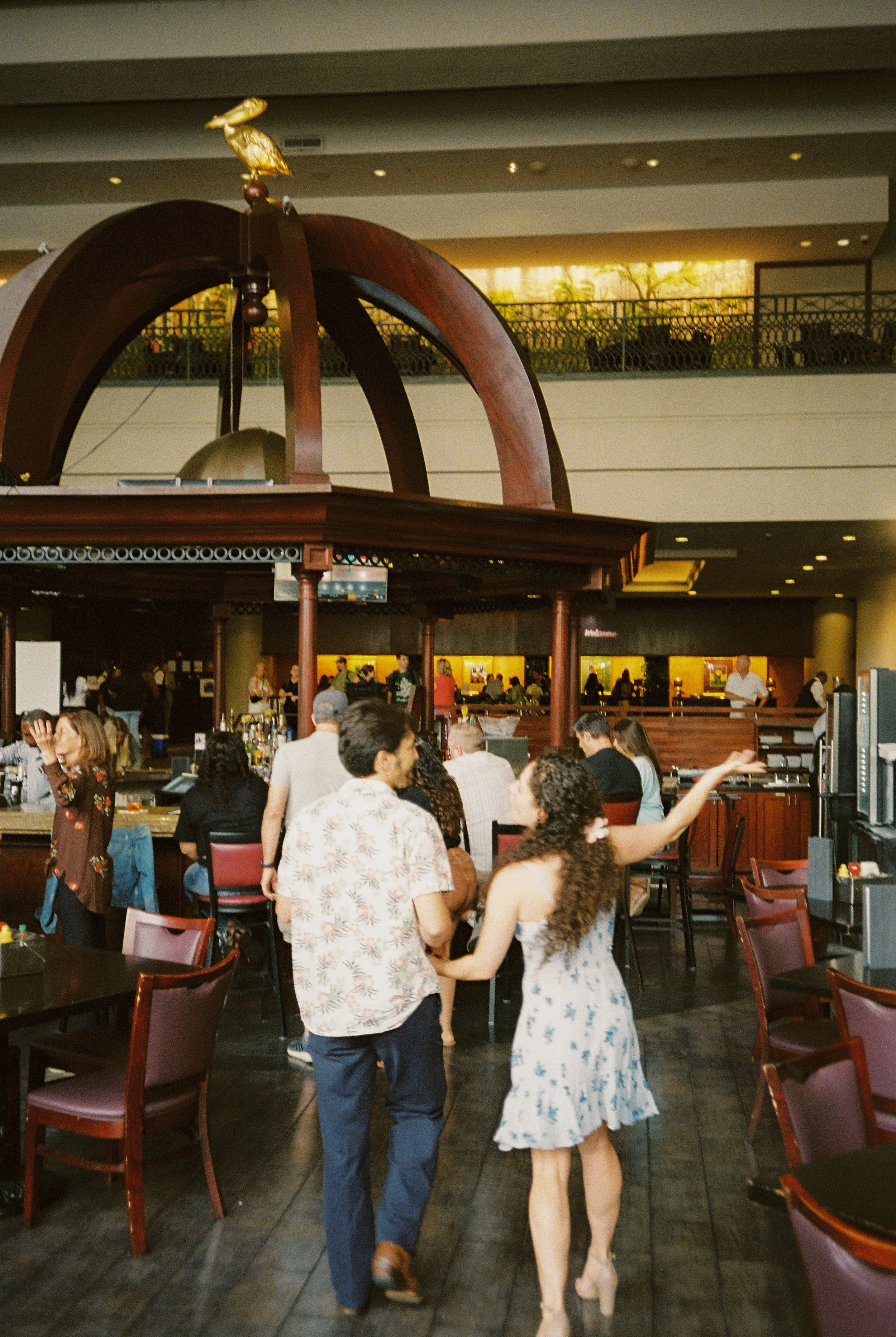 Couple walking hand in hand through the restaurant during their wedding rehearsal dinner.