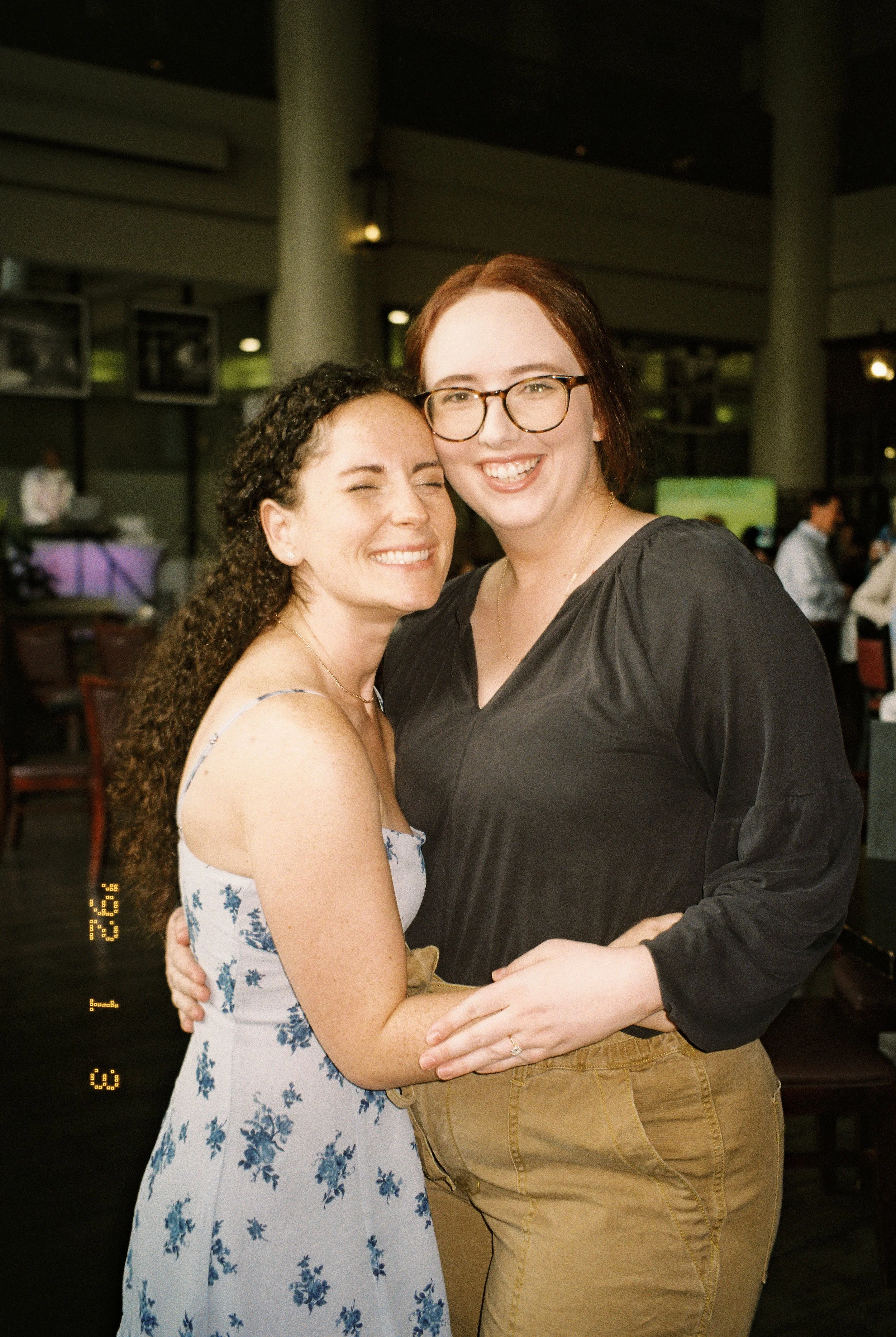 Two women hugging and smiling for a candid portrait during the celebration.