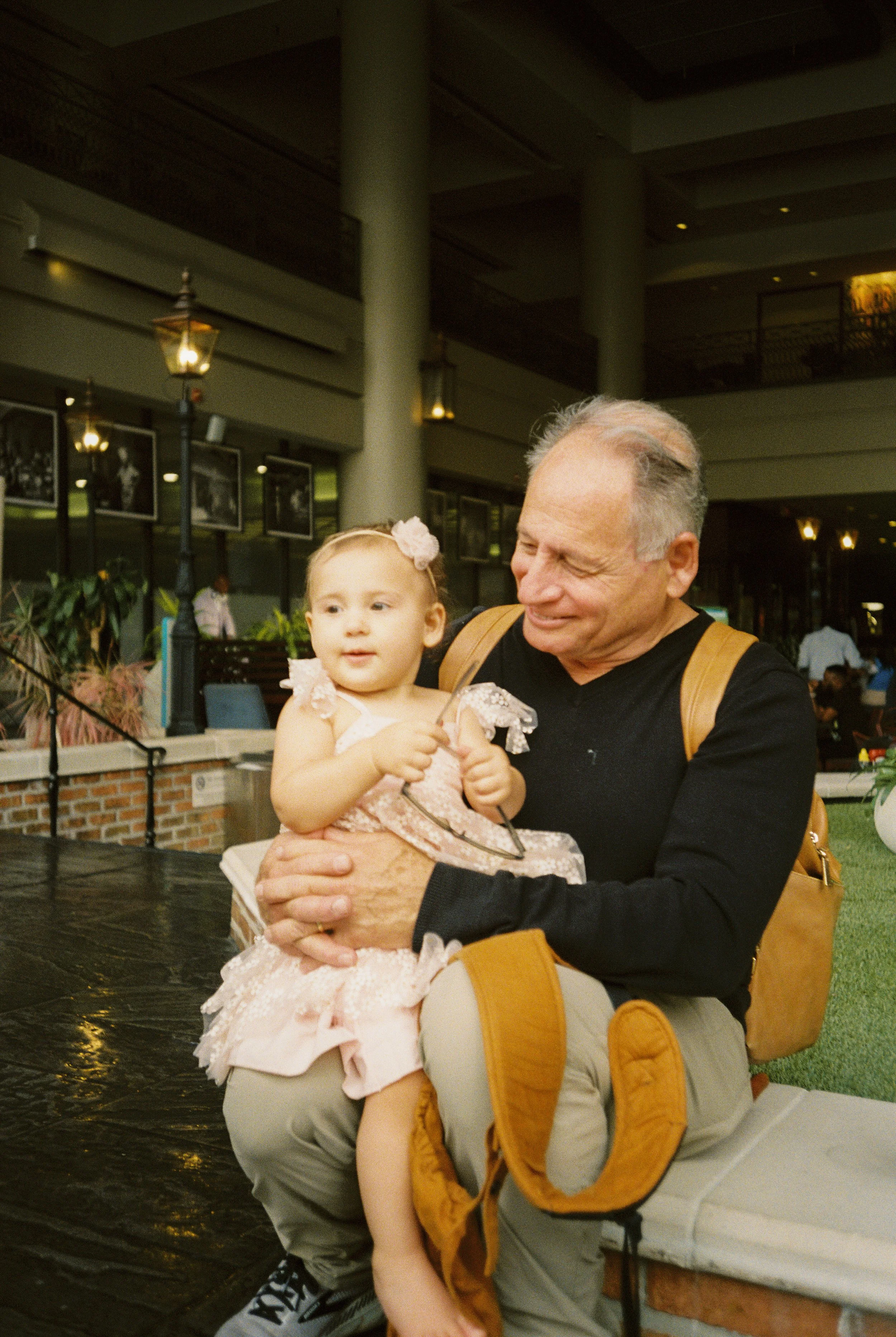 Grandfather holding a young girl in a pink dress during the family celebration.