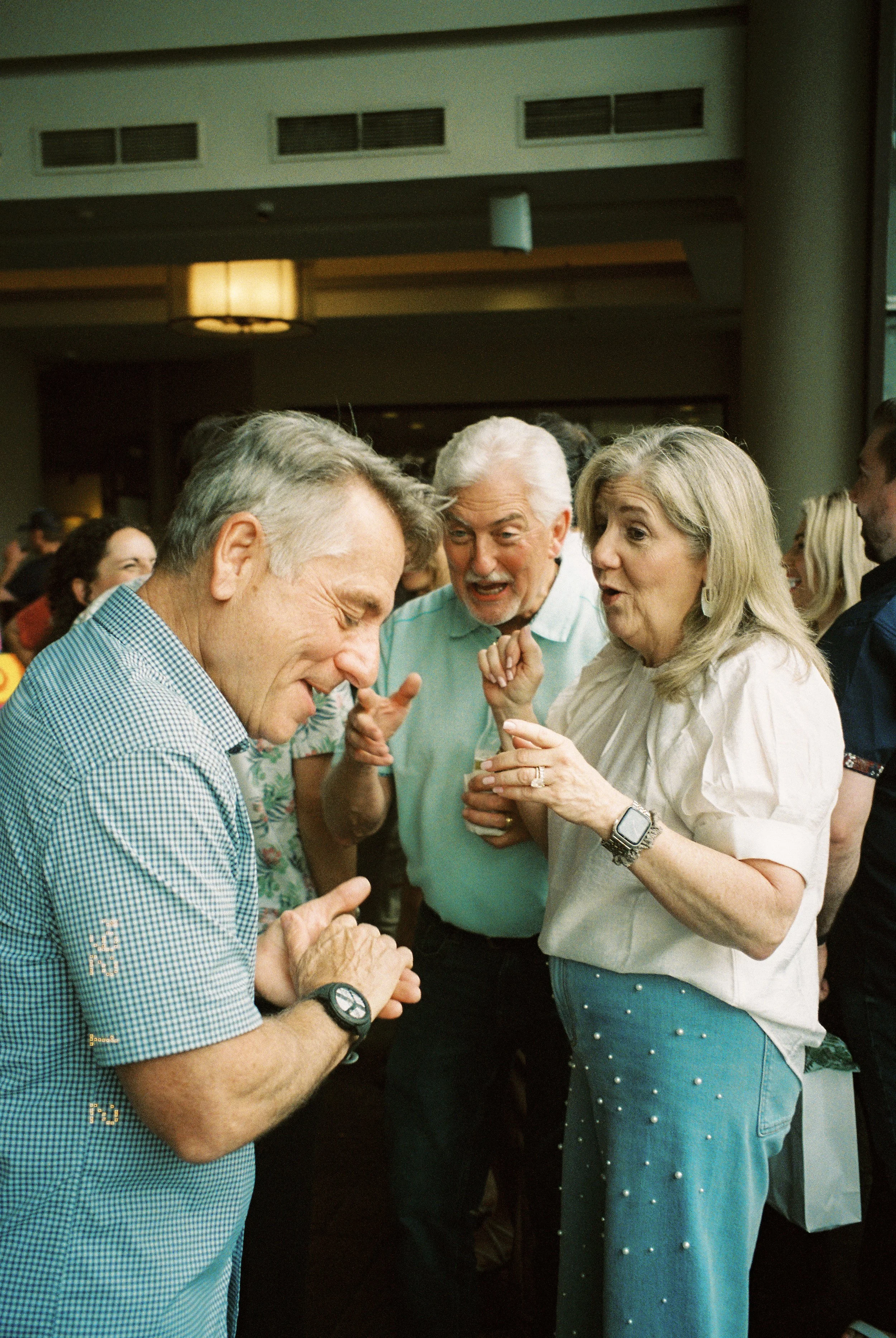 Guests laughing and sharing stories while mingling during the wedding rehearsal dinner.