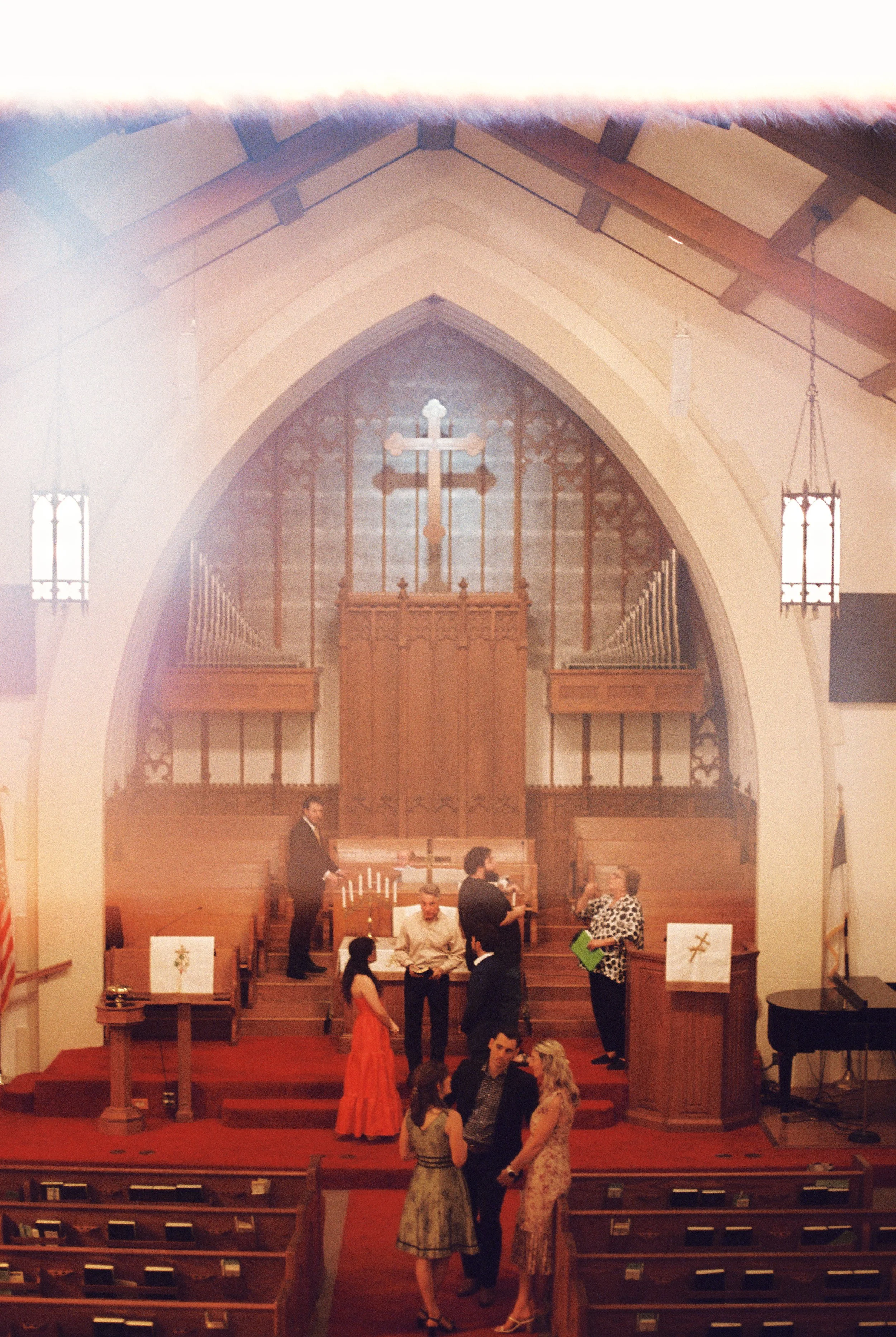 Wide view of family and friends gathering inside the church for the wedding rehearsal before dinner.