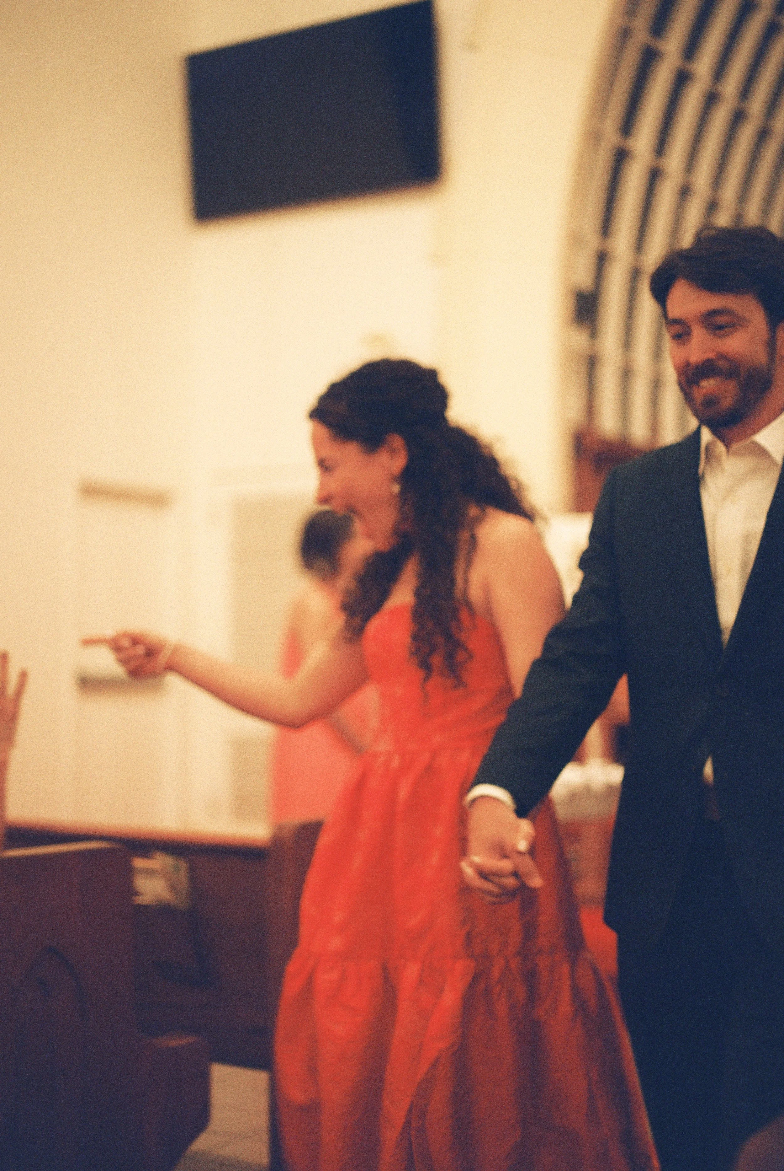 Couple holding hands and laughing as they walk through the church during their rehearsal.