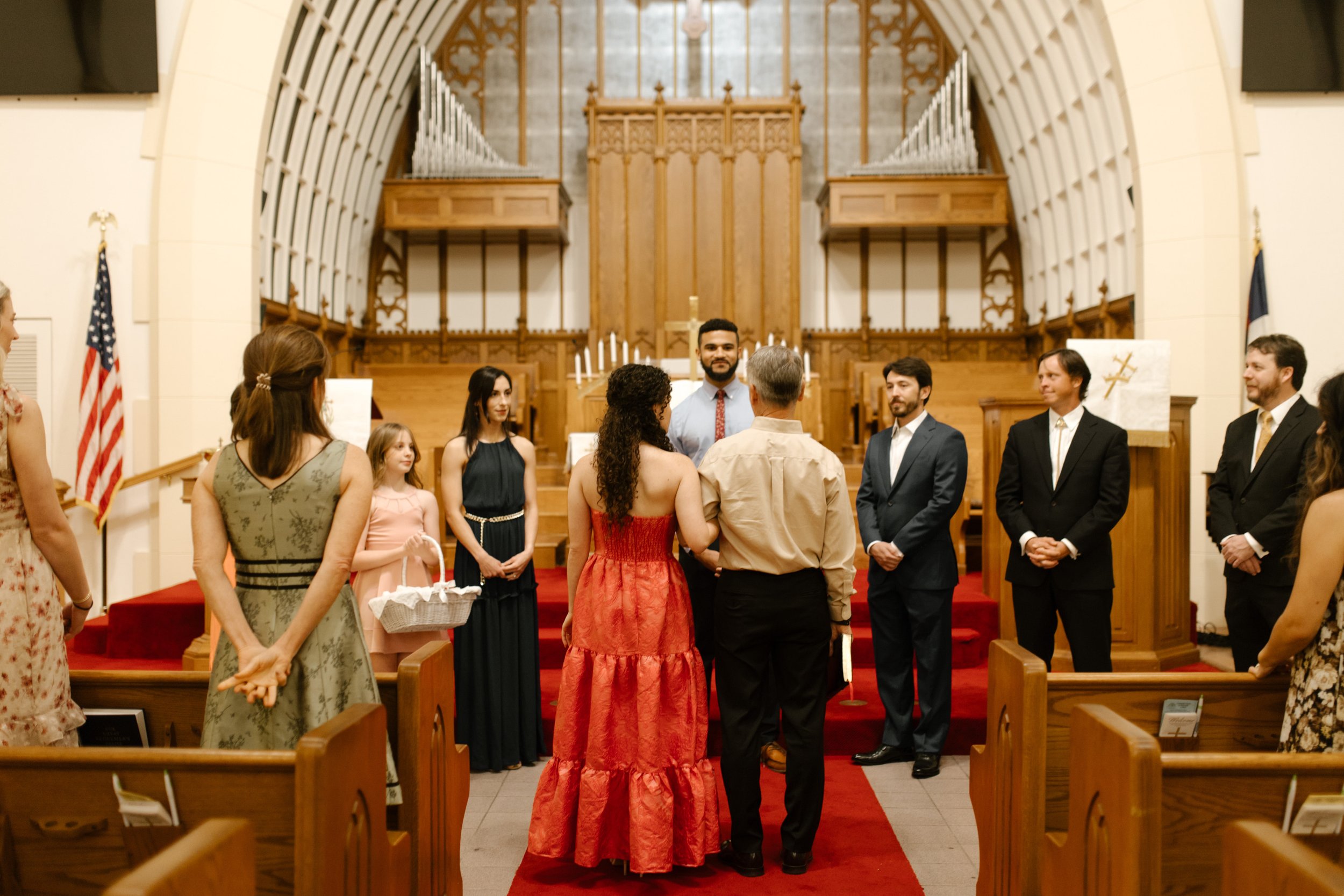 Wedding party gathered at the front of the church while practicing the ceremony during the wedding rehearsal.