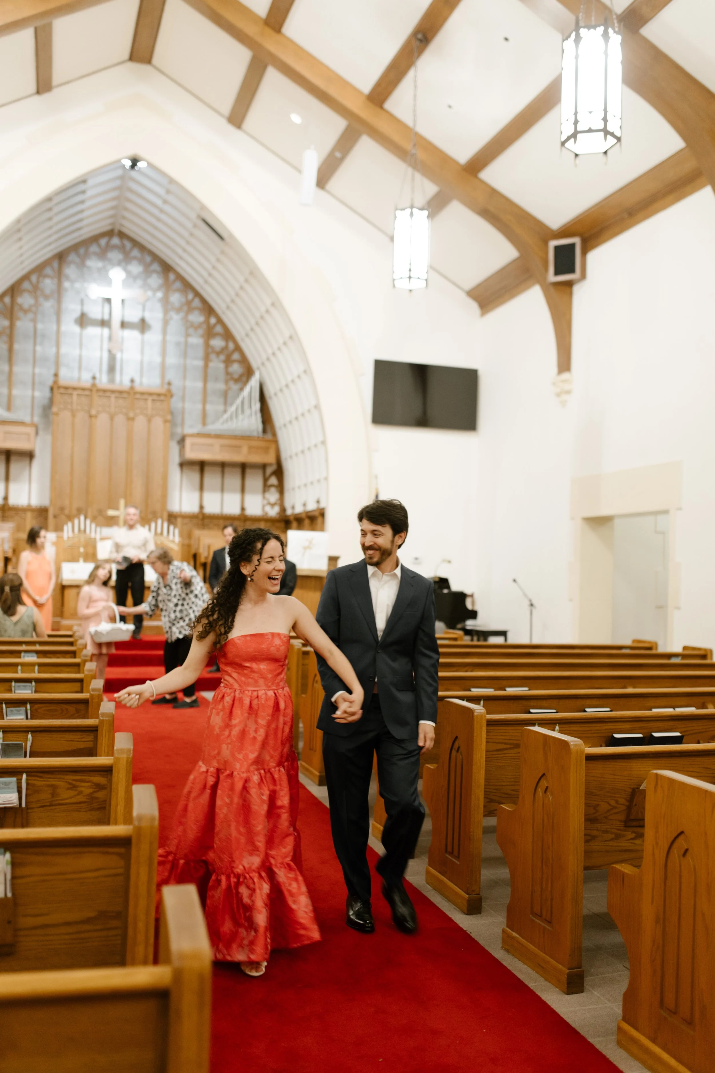 Couple laughing as they walk hand in hand down the church aisle during their wedding rehearsal dinner weekend.