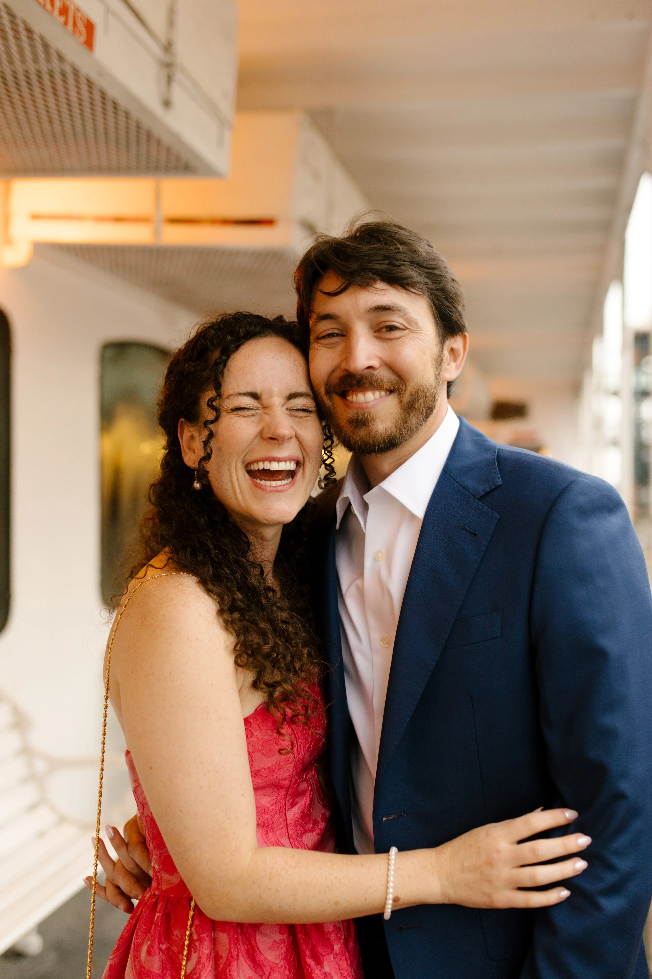 Couple smiling and laughing together on the riverboat deck before their wedding celebration.