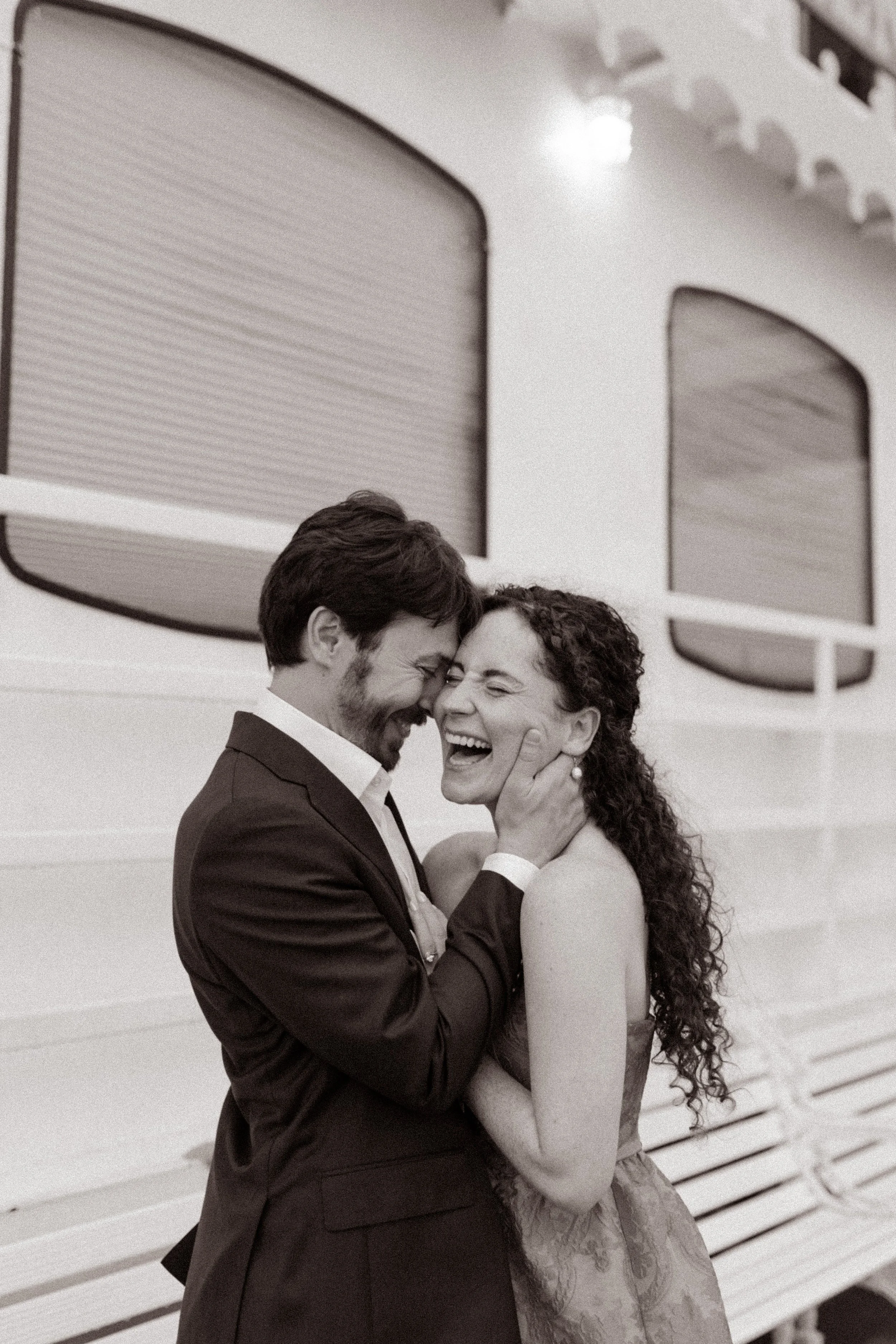 Black-and-white portrait of the couple laughing together on the deck of the riverboat.