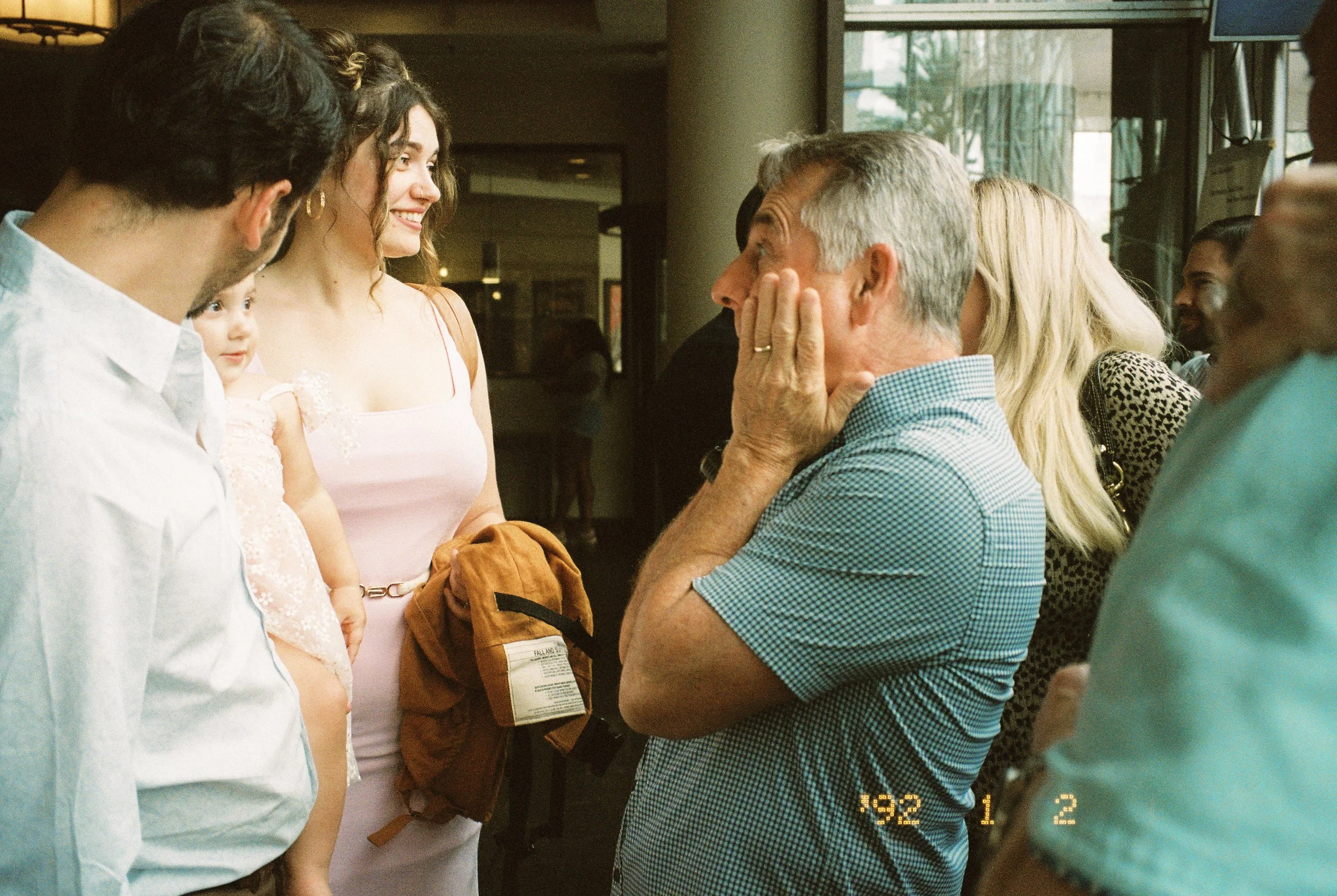 Family and friends gathering around a baby while laughing together at the pre-wedding celebration.