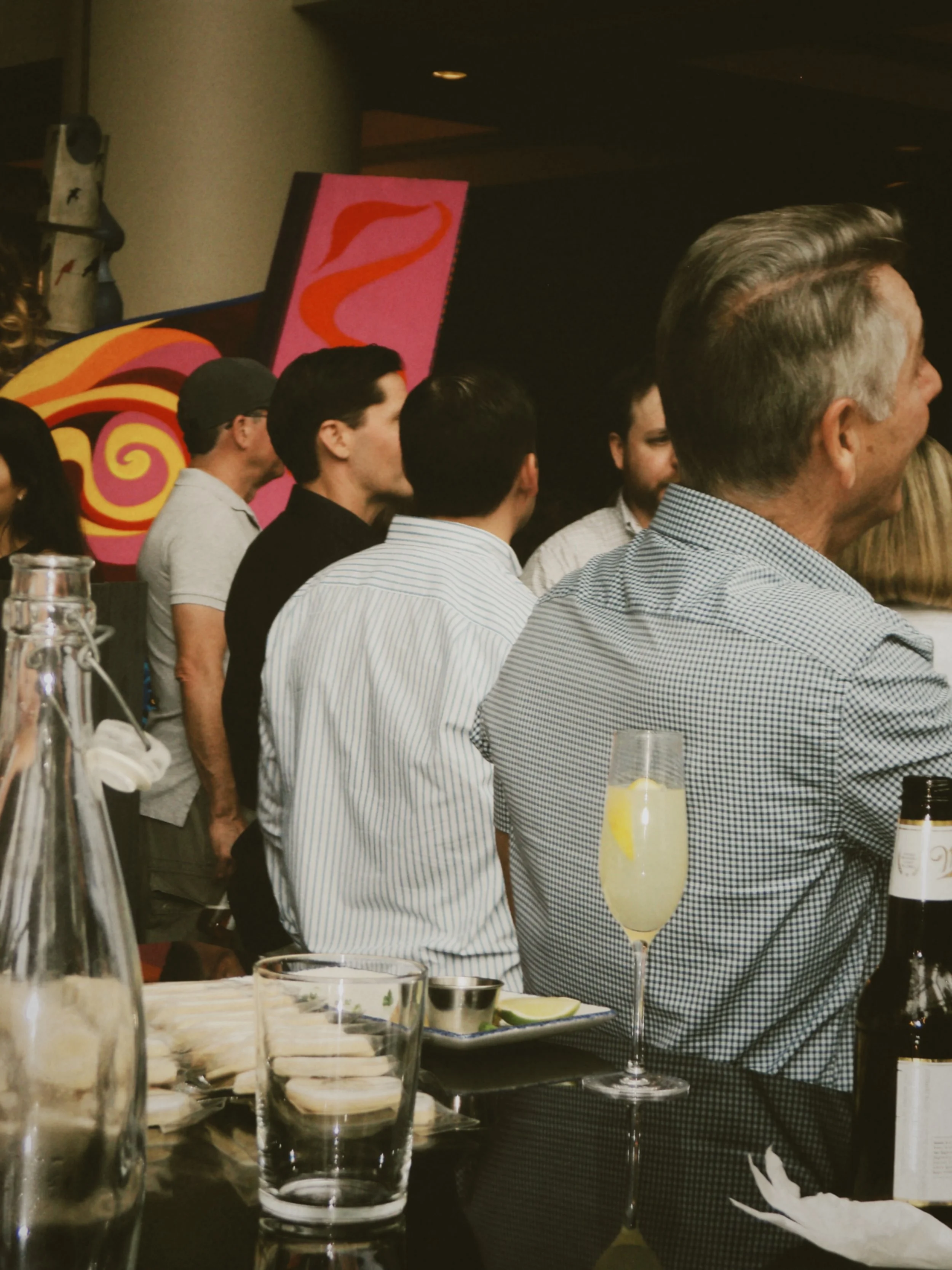 Guests mingling near the bar with cocktails and appetizers during the evening gathering.