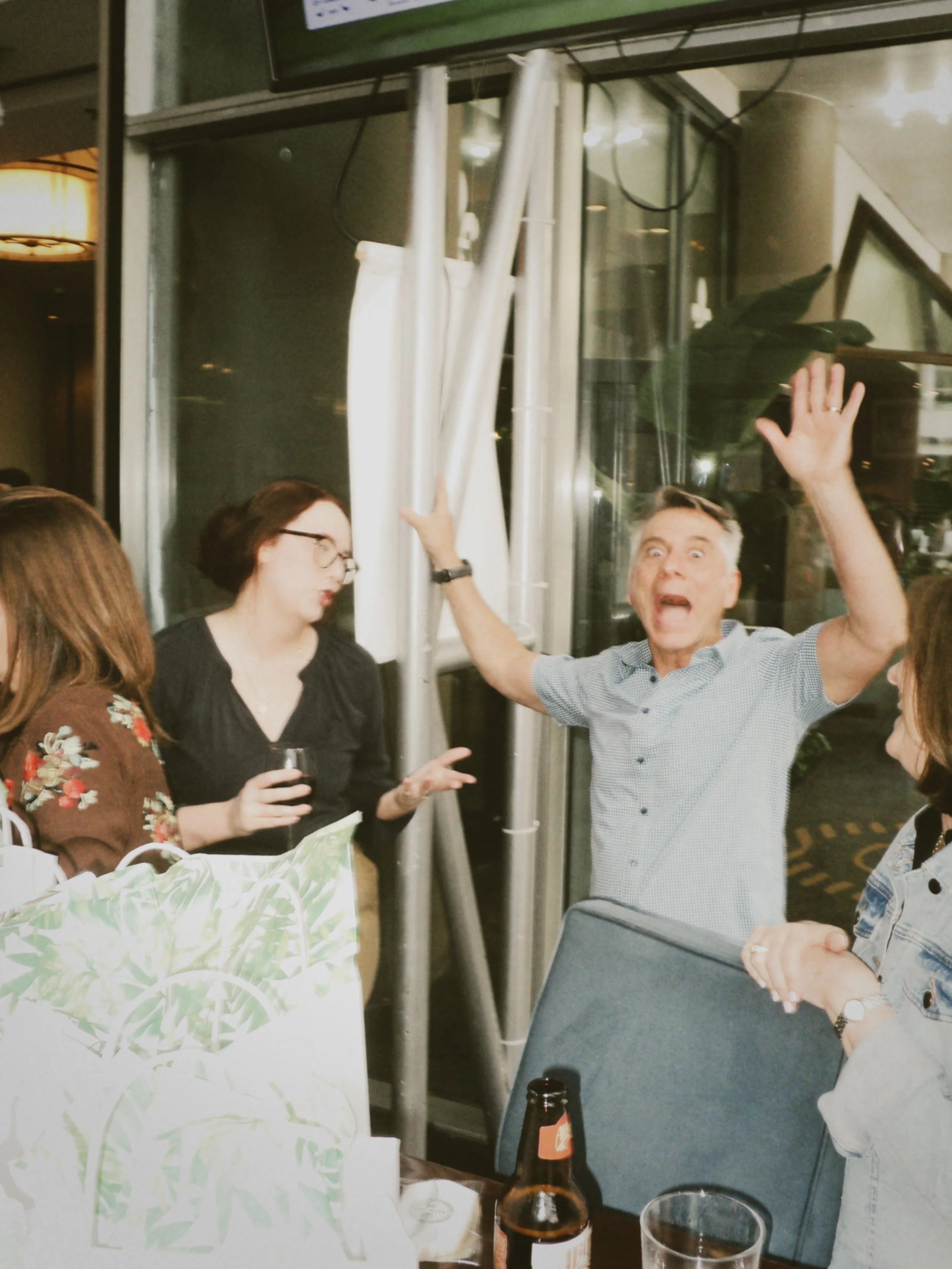 Guest throwing his hands up with a playful expression while mingling during the wedding rehearsal dinner.