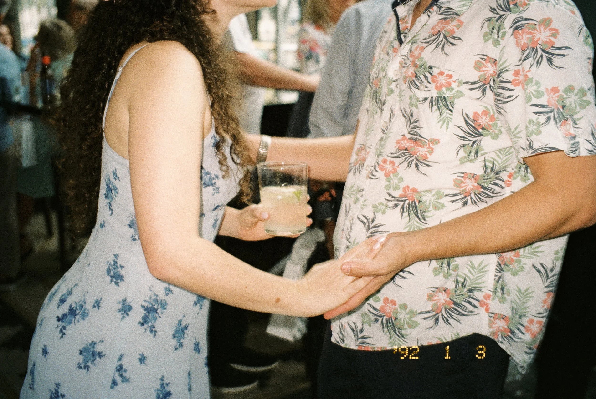 Couple holding hands while mingling with guests and enjoying drinks at their wedding rehearsal dinner.