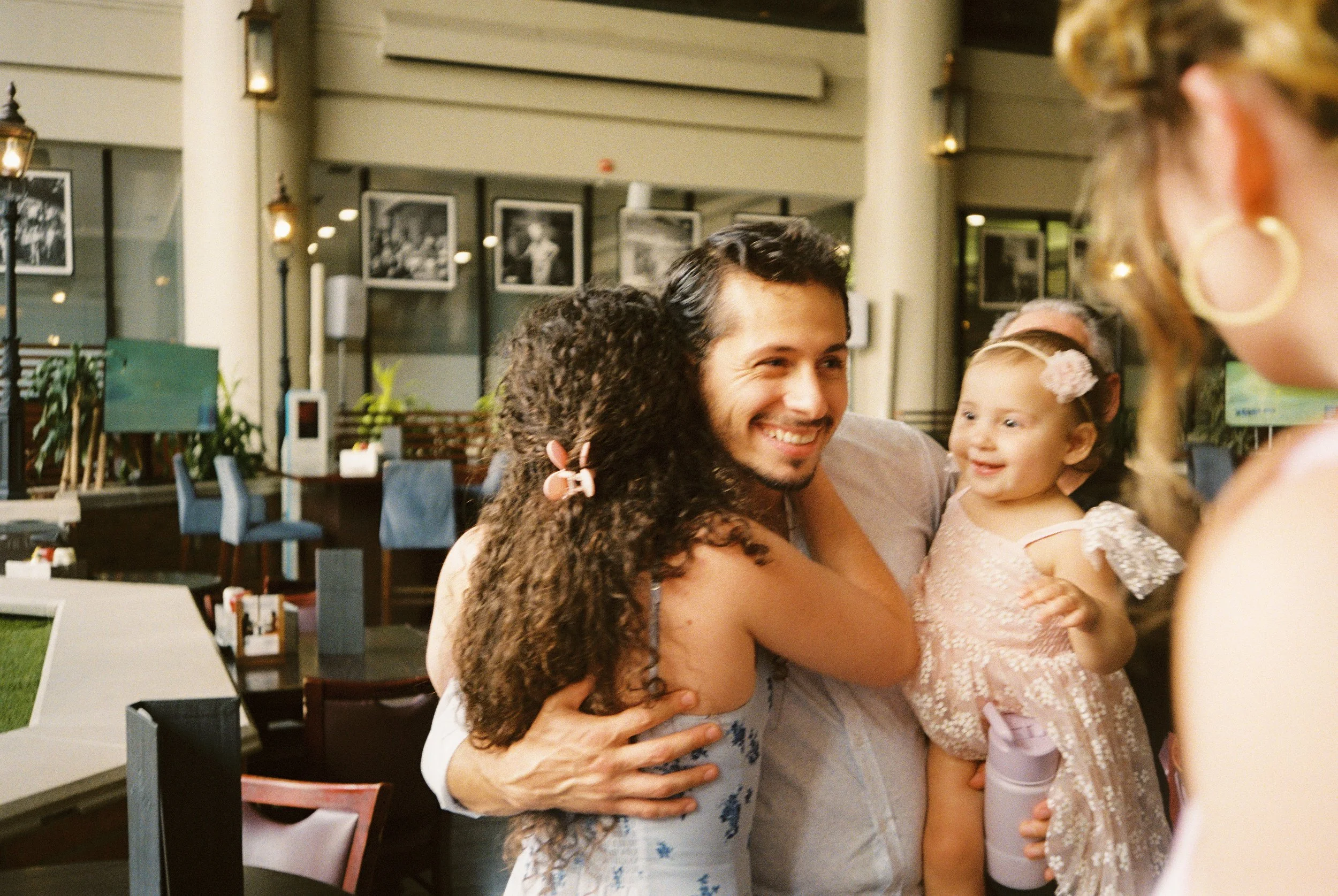 Woman hugging a guest holding a young child during a joyful family gathering before the wedding.