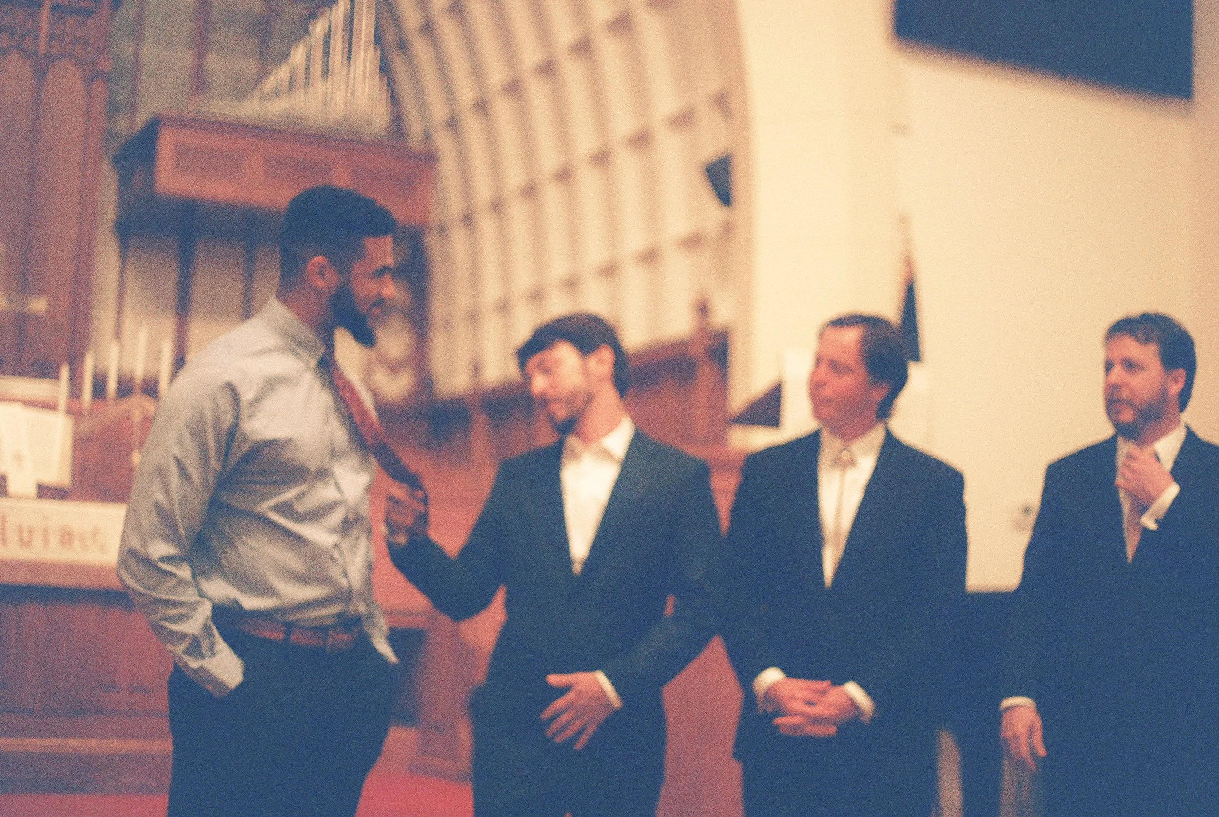Groom-to-be laughing with members of the wedding party during the ceremony rehearsal.