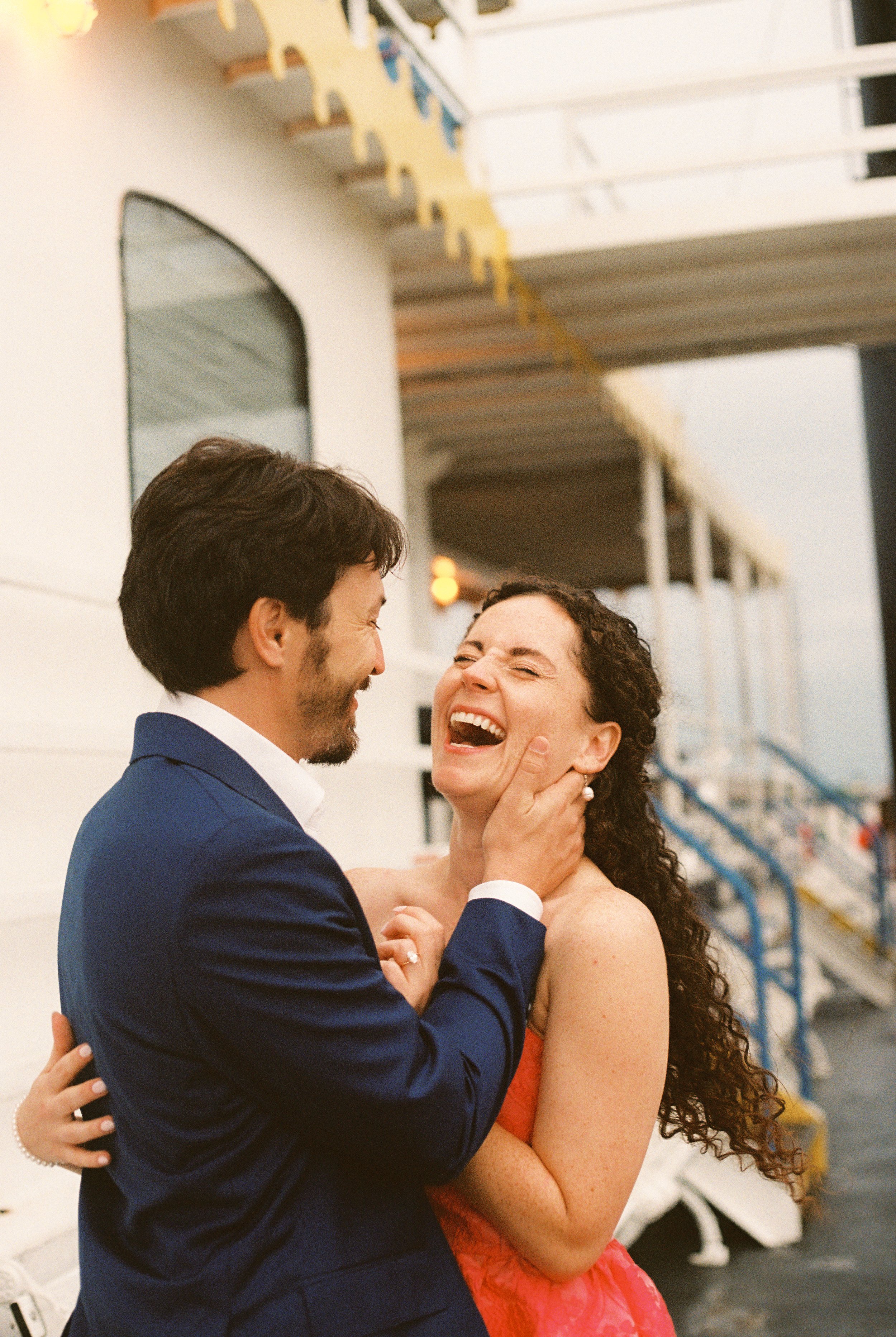 Couple laughing together on the riverboat deck during a playful portrait before the wedding.
