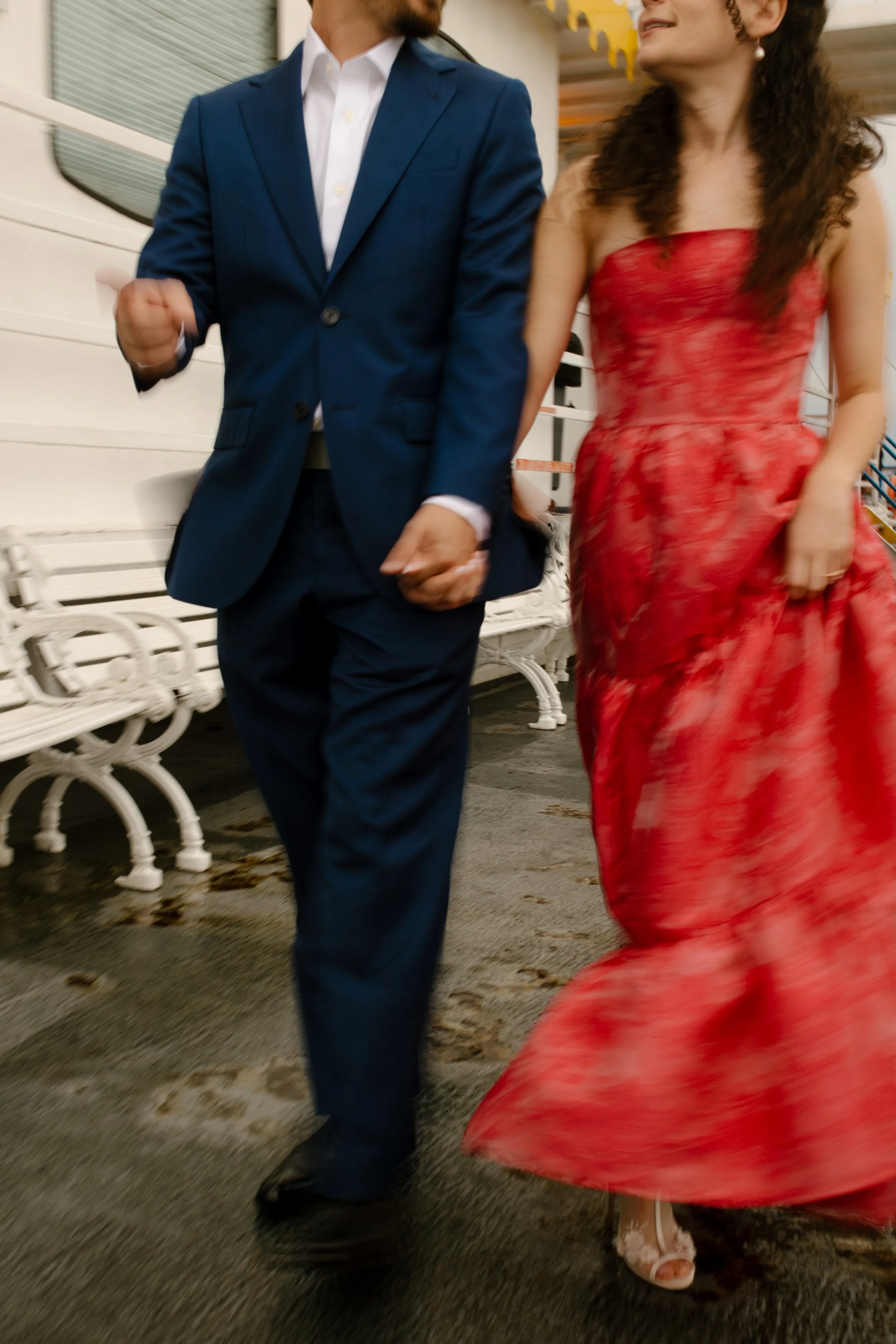 Couple walking hand in hand along the riverboat deck during their wedding rehearsal dinner celebration.