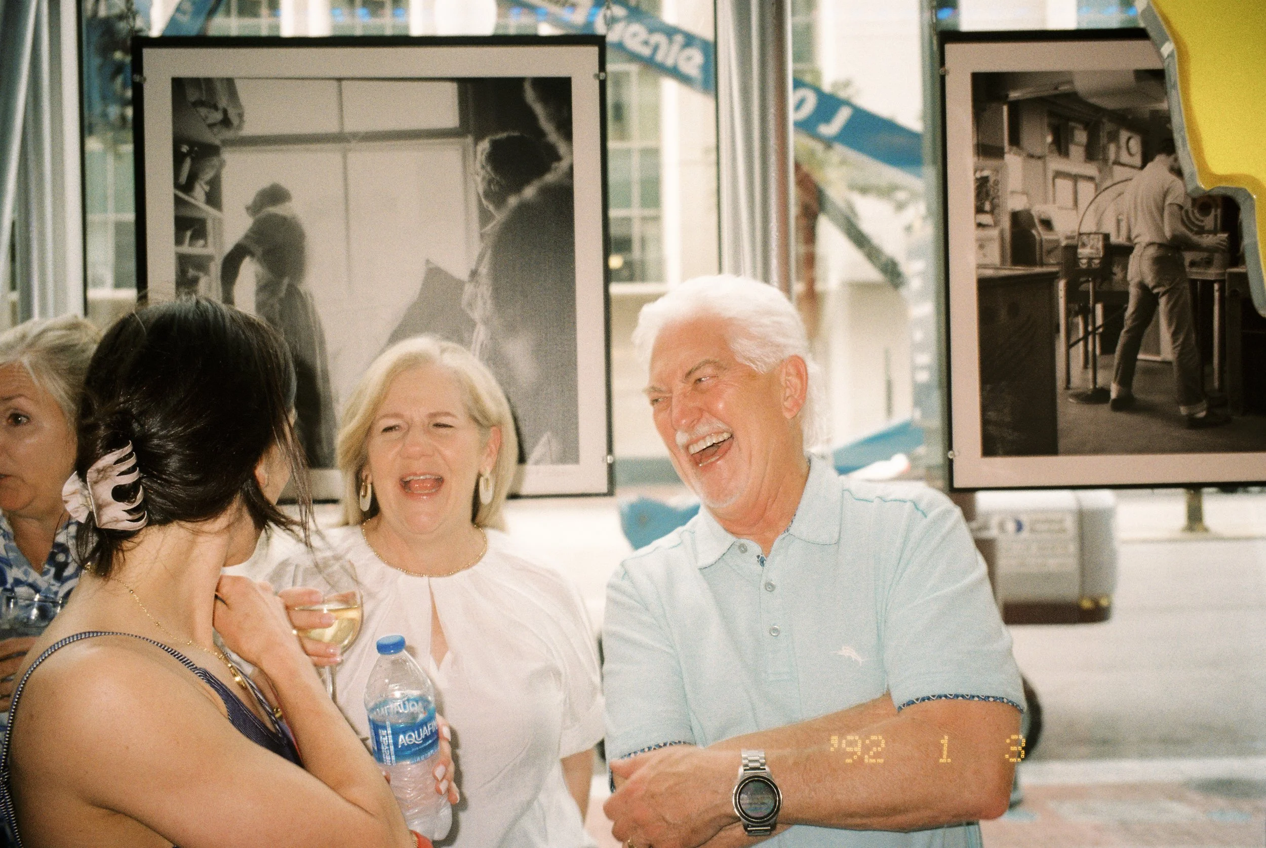 Family members laughing together over drinks during the wedding rehearsal dinner gathering.