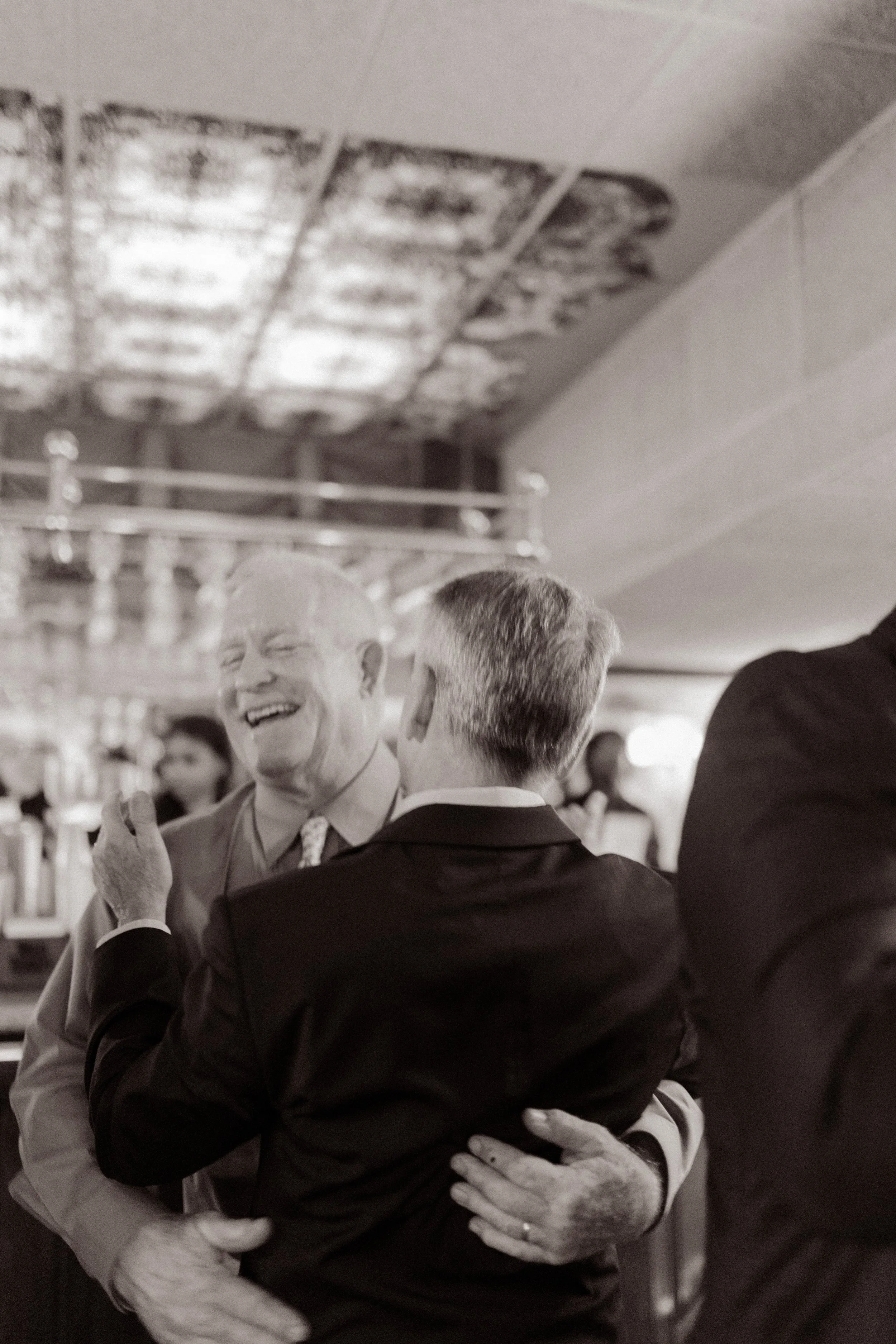 Two guests sharing a warm hug during an evening celebration with family and friends.