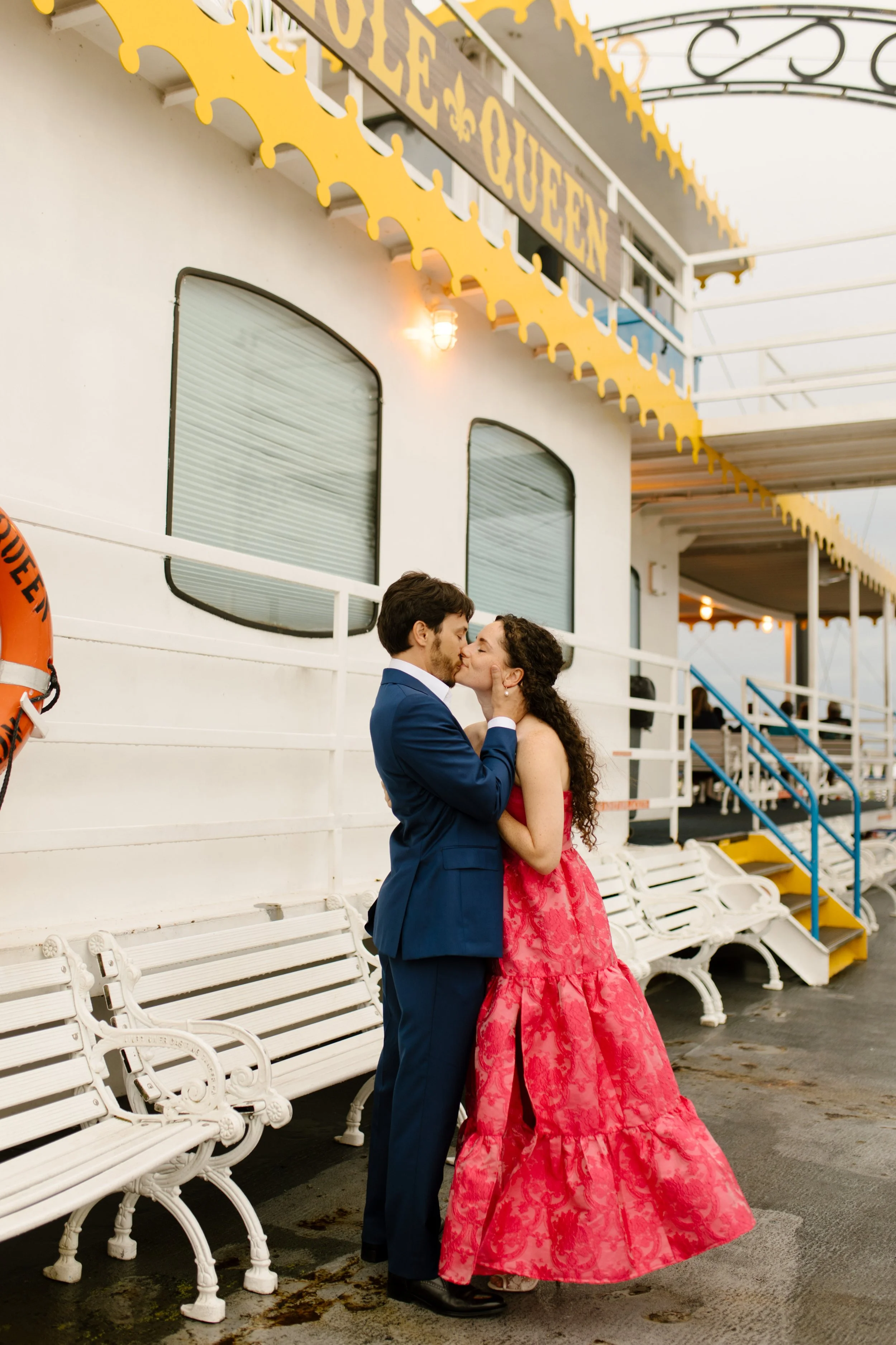 Couple sharing a kiss on the riverboat deck before their wedding rehearsal dinner celebration.