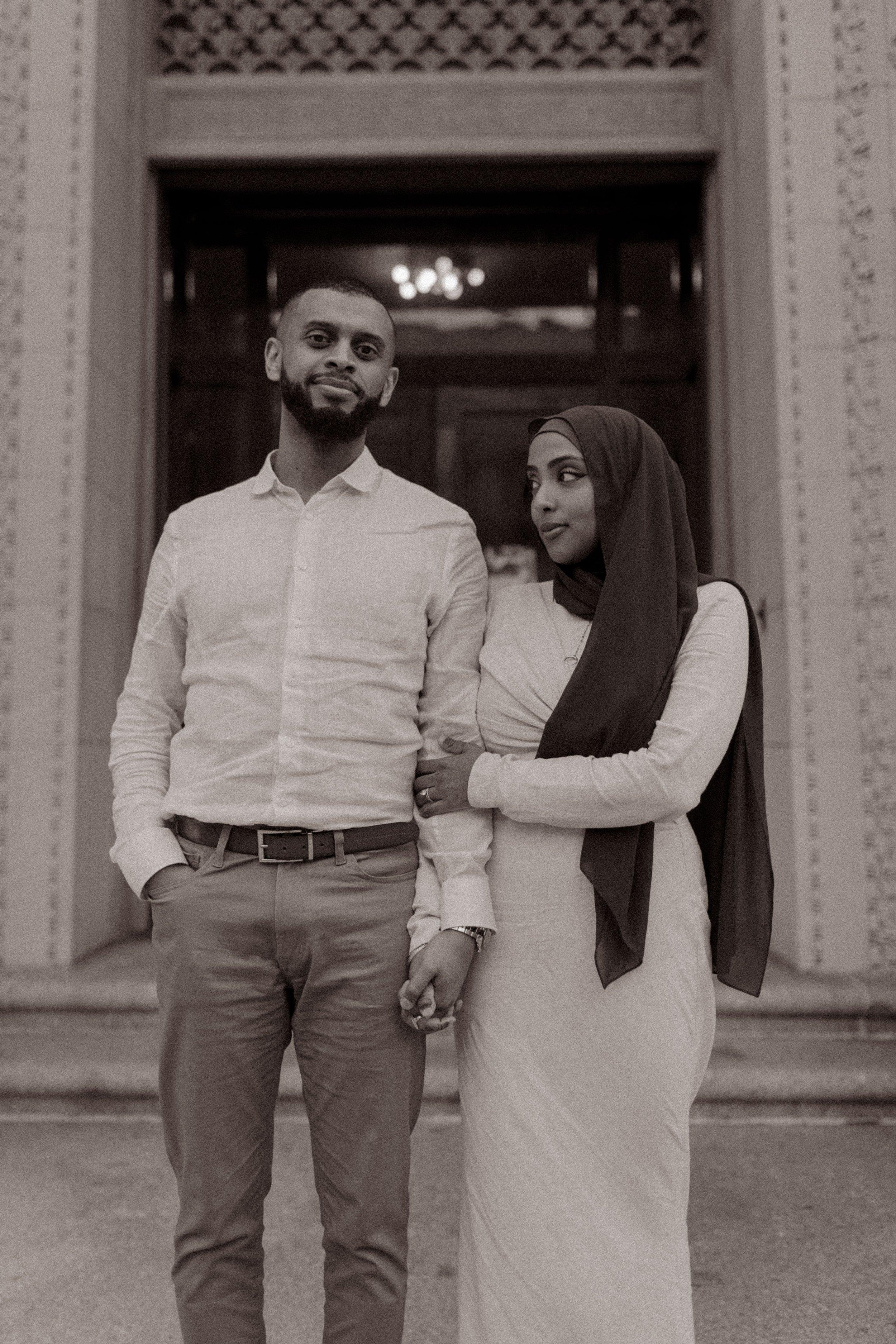 Couple holding hands outside a courthouse in a black and white wedding portrait