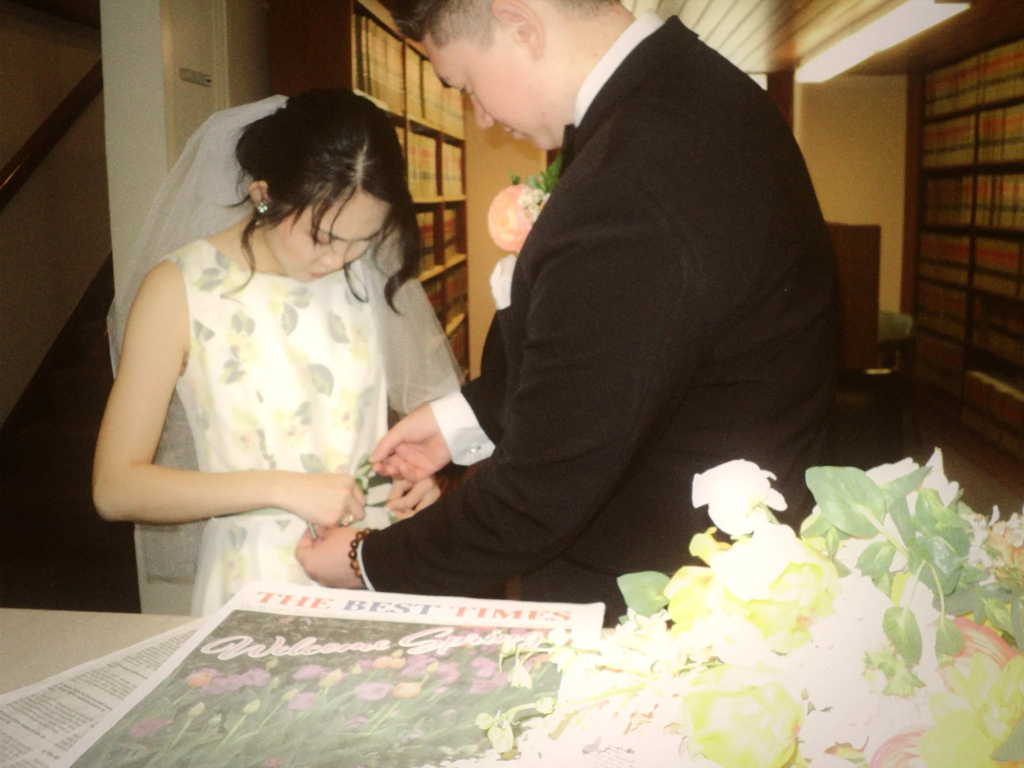 Newlyweds adjusting wedding details together beside their bouquet and personalized newspaper