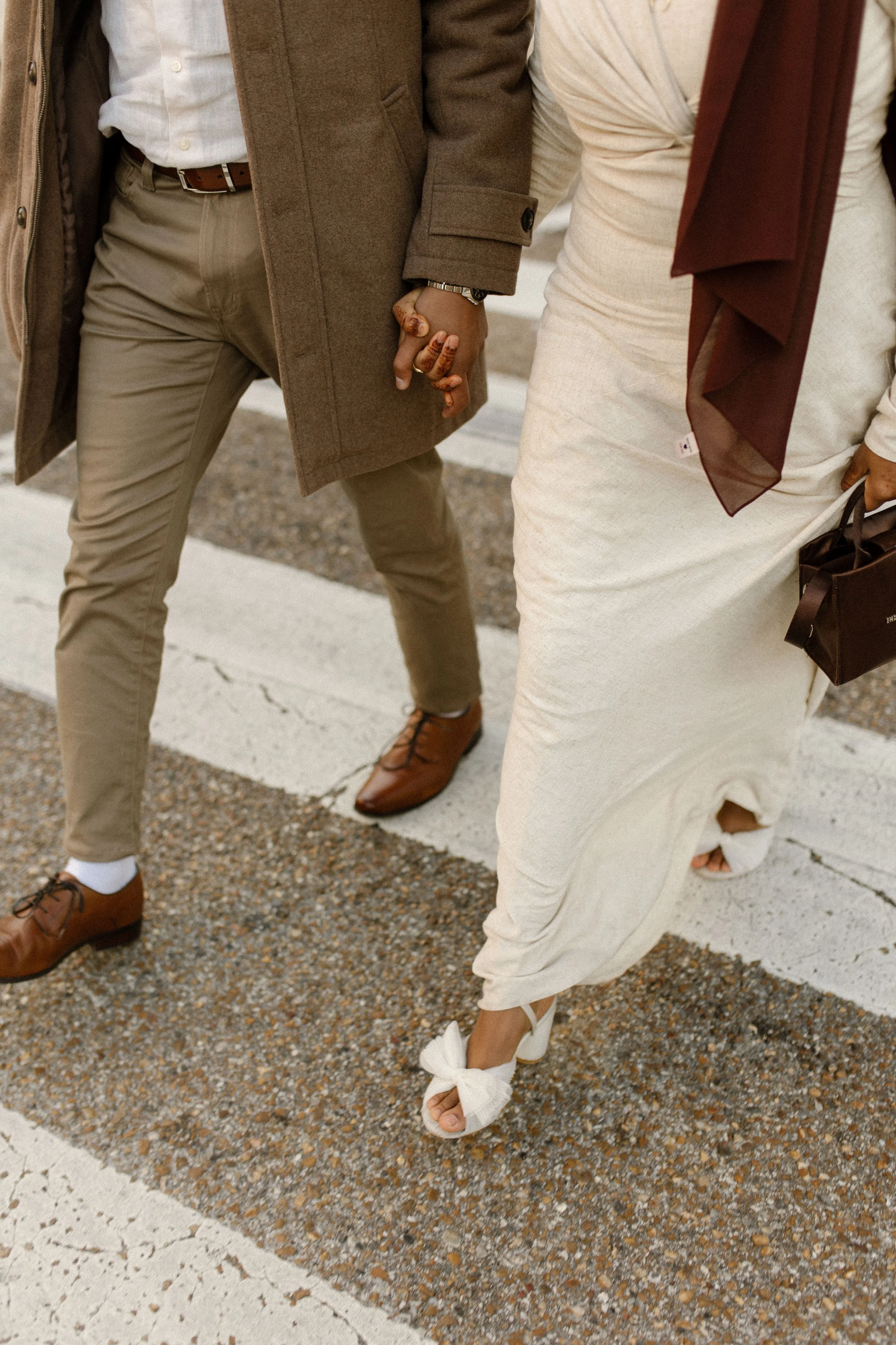 Close-up of a couple holding hands while walking in wedding attire and statement shoes.