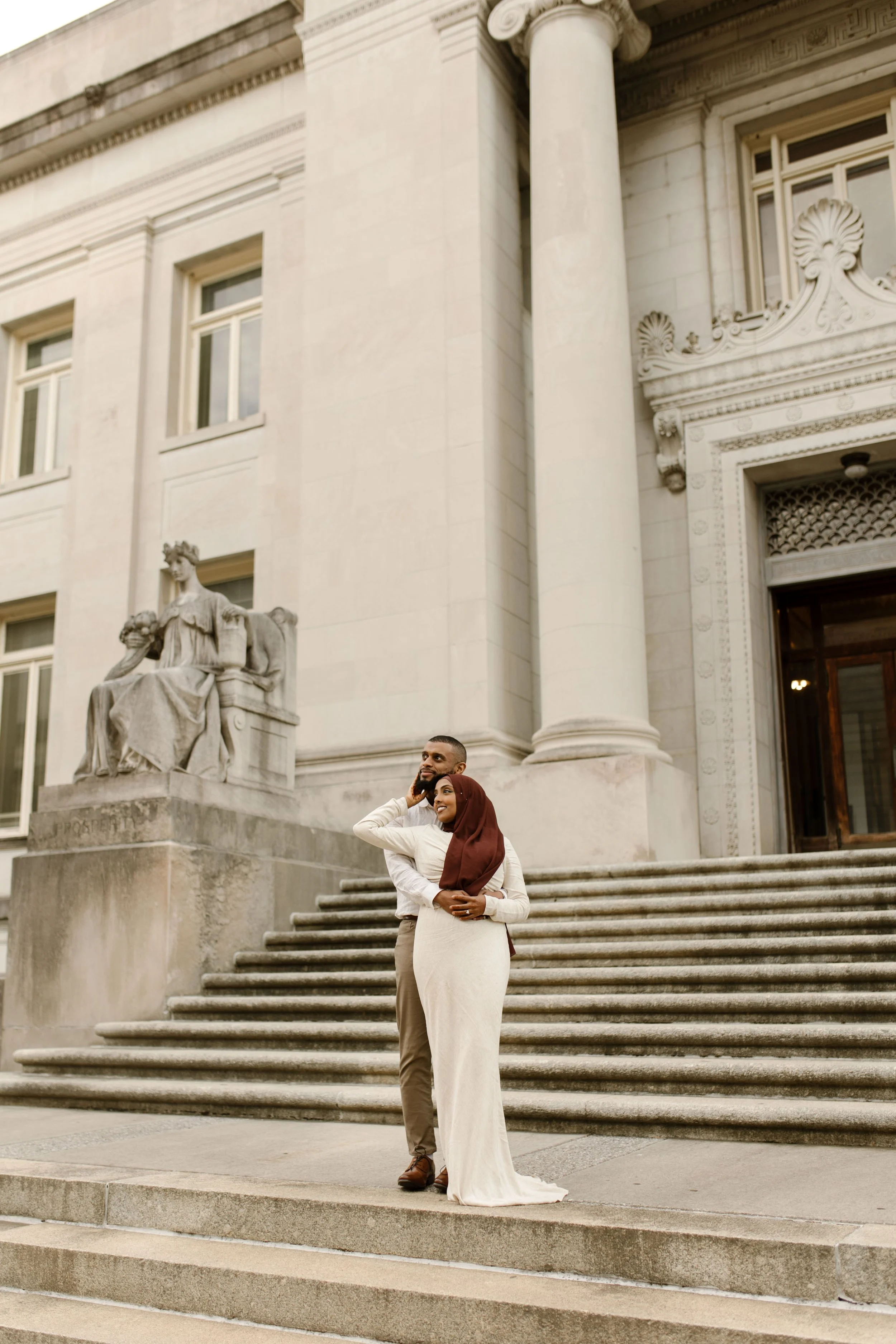 Couple embracing on courthouse steps in elegant, understated wedding attire