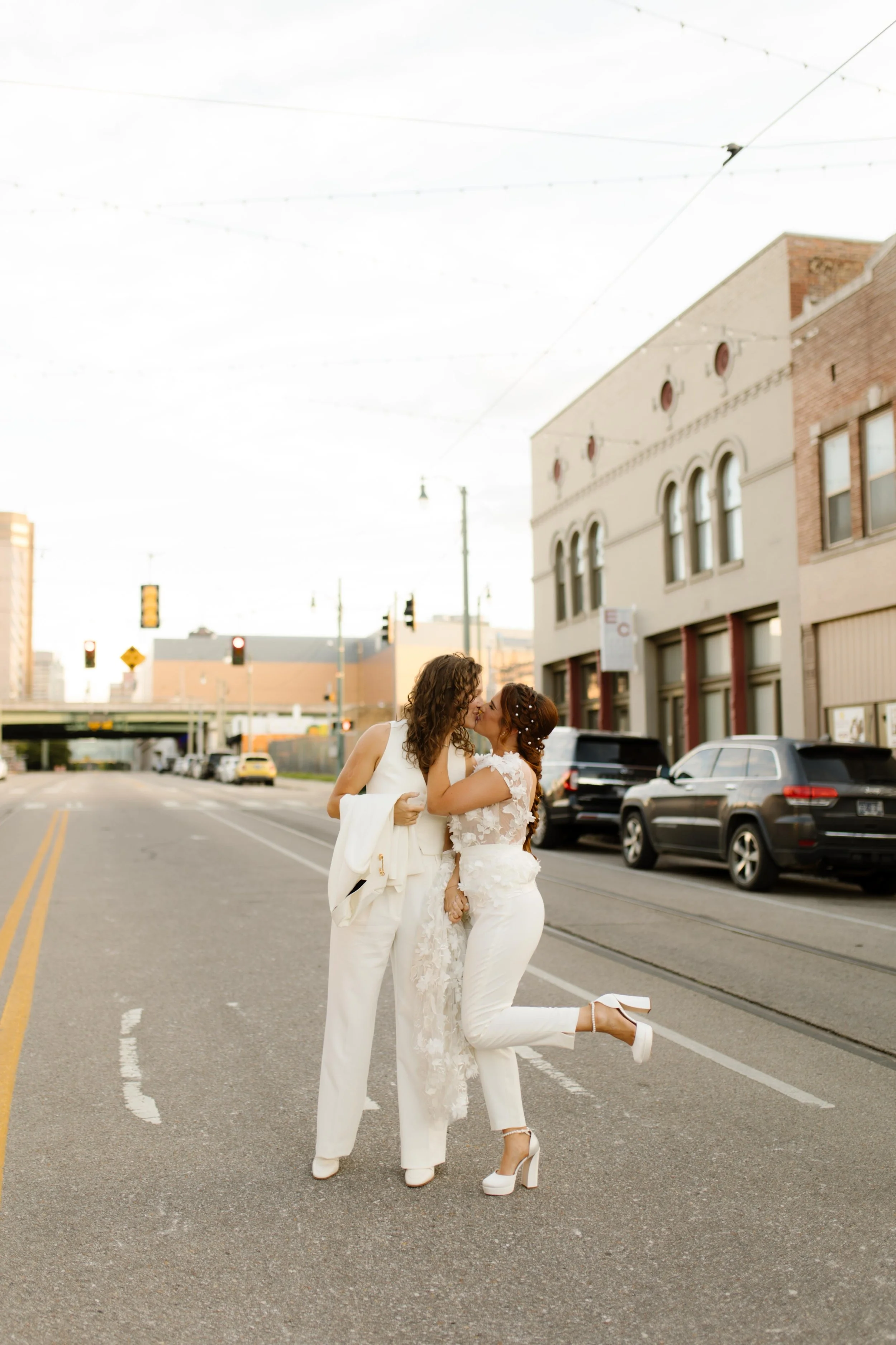 New York City courthouse wedding brides kissing in the street wearing a lace wedding dress and modern white suit