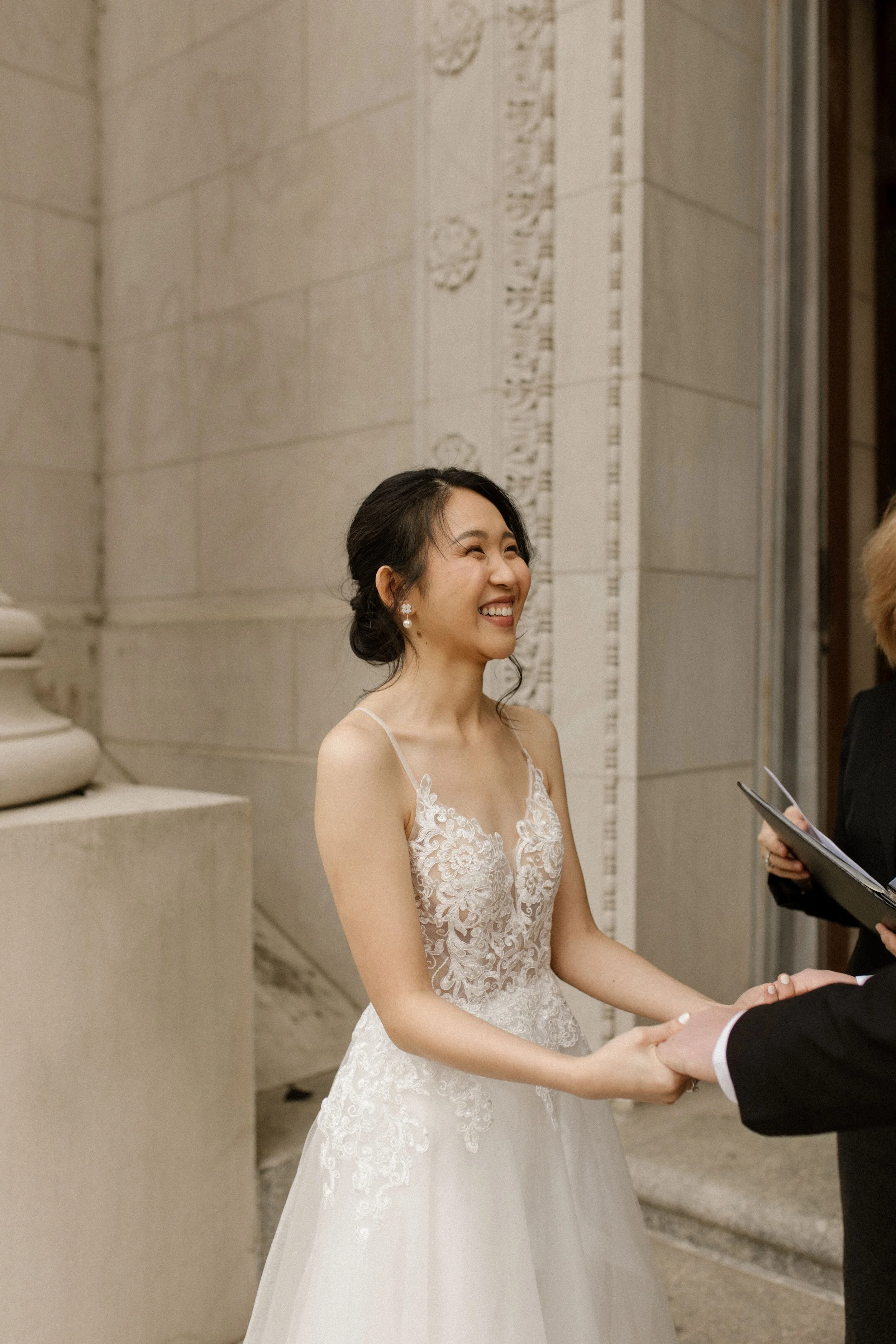 Bride smiling during her courthouse wedding ceremony in a lace wedding gown