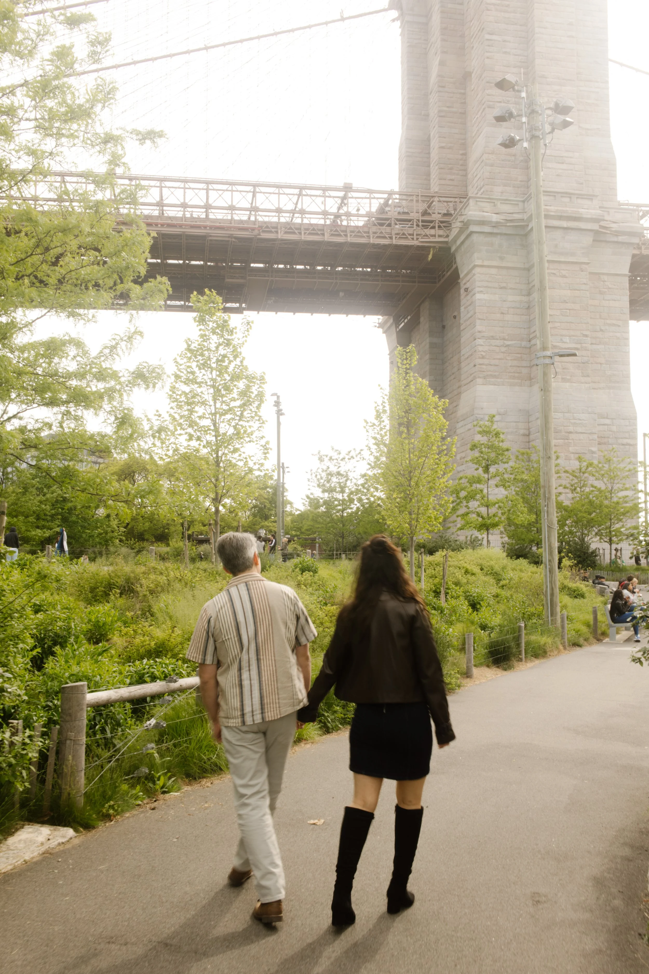 Couple walking beneath the Brooklyn Bridge during an engagement session at iconic wedding locations in New York.