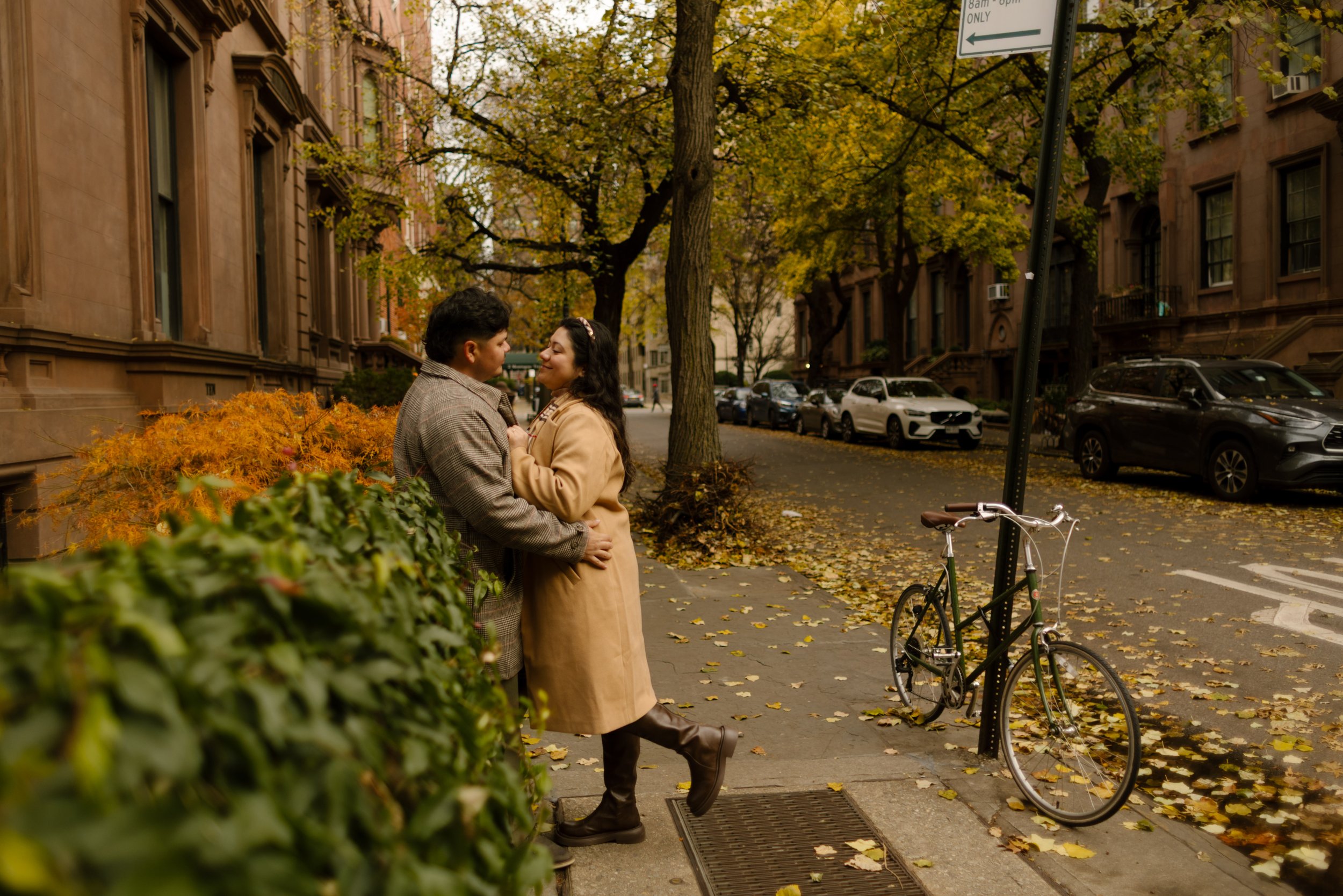 Couple embracing on a tree-lined Brooklyn brownstone street during a romantic fall engagement session.
