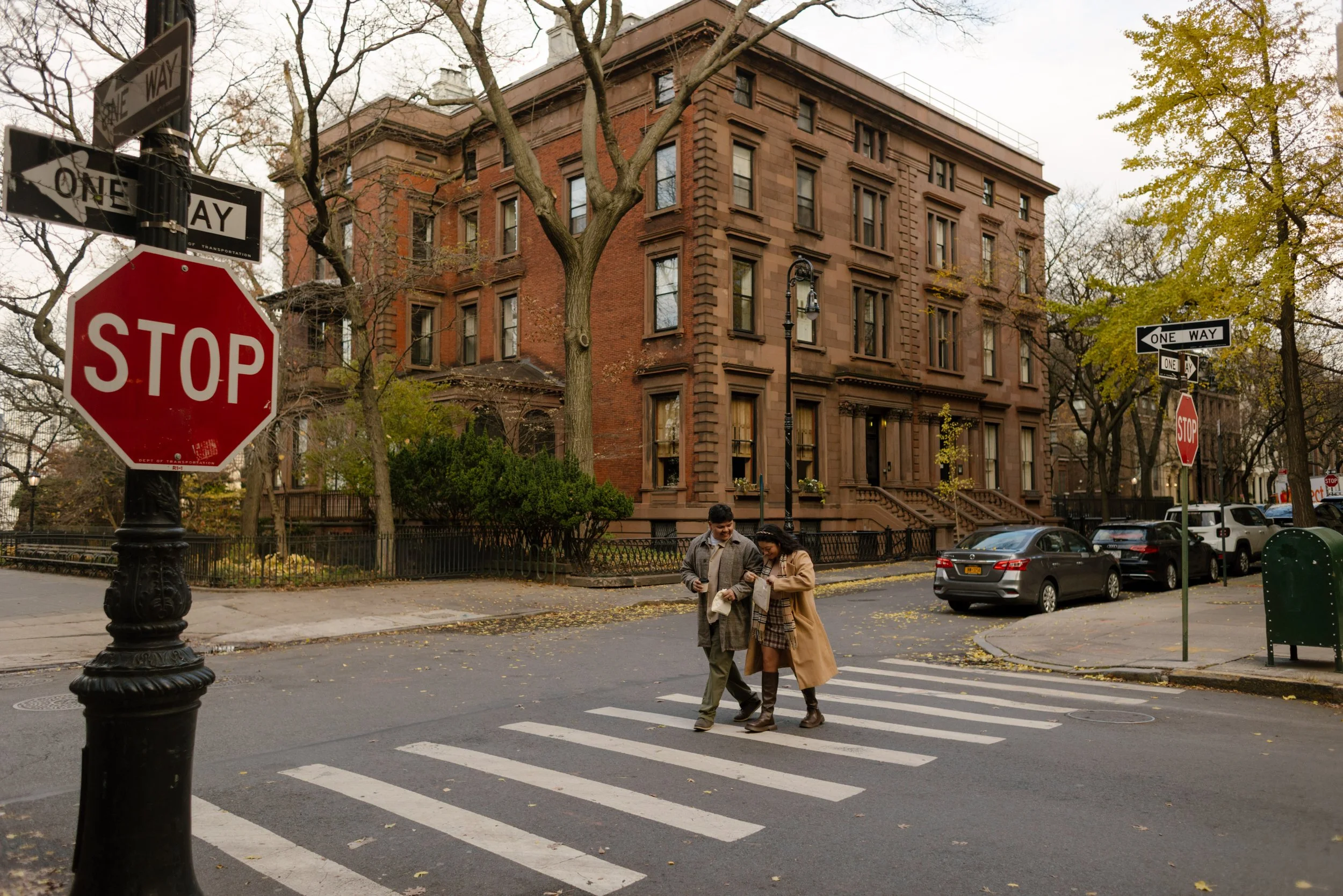 Couple crossing a Brooklyn street lined with historic brownstones, showcasing charming wedding locations in New York.