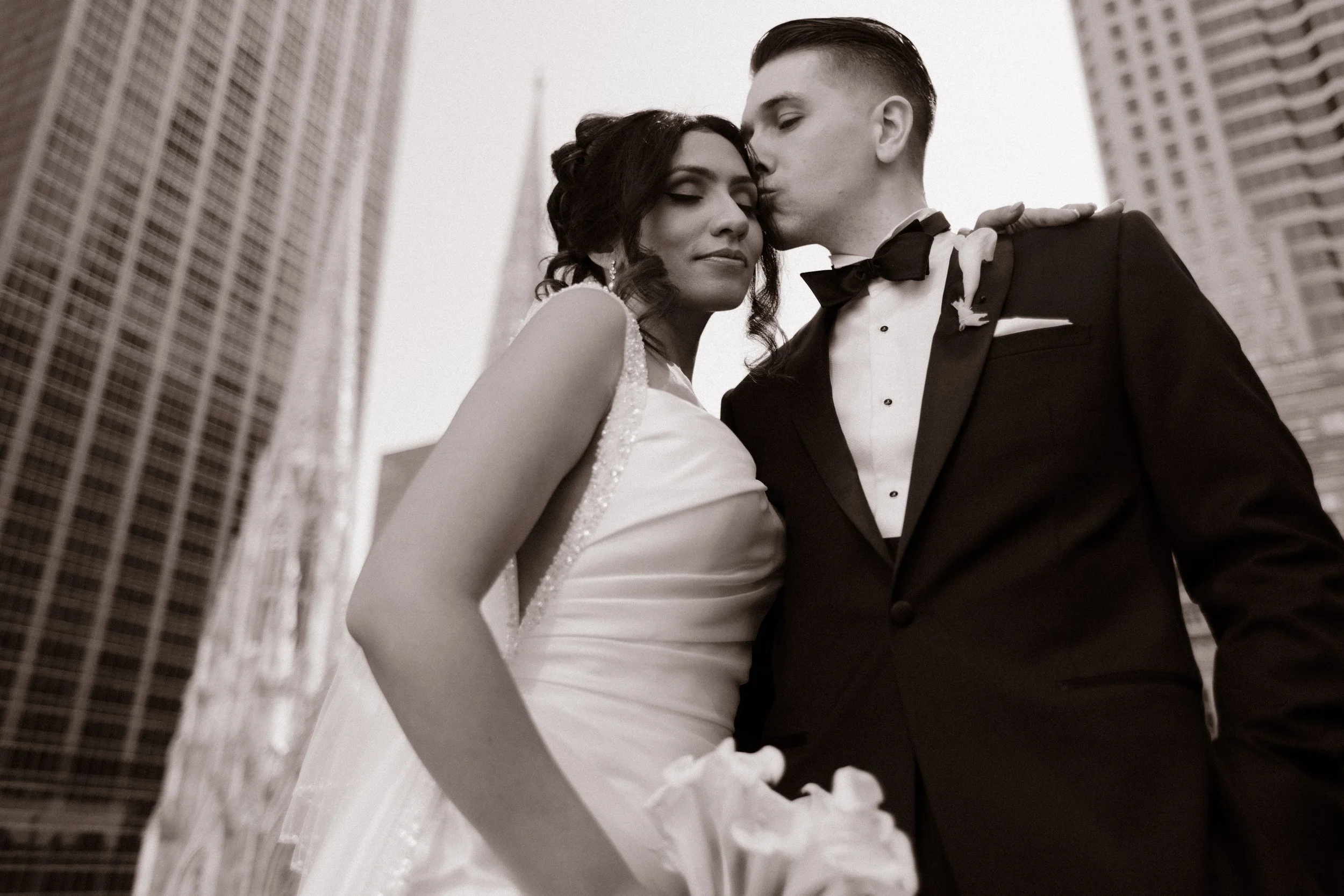 Black-and-white low-angle wedding portrait of a bride and groom surrounded by New York City skyscrapers.