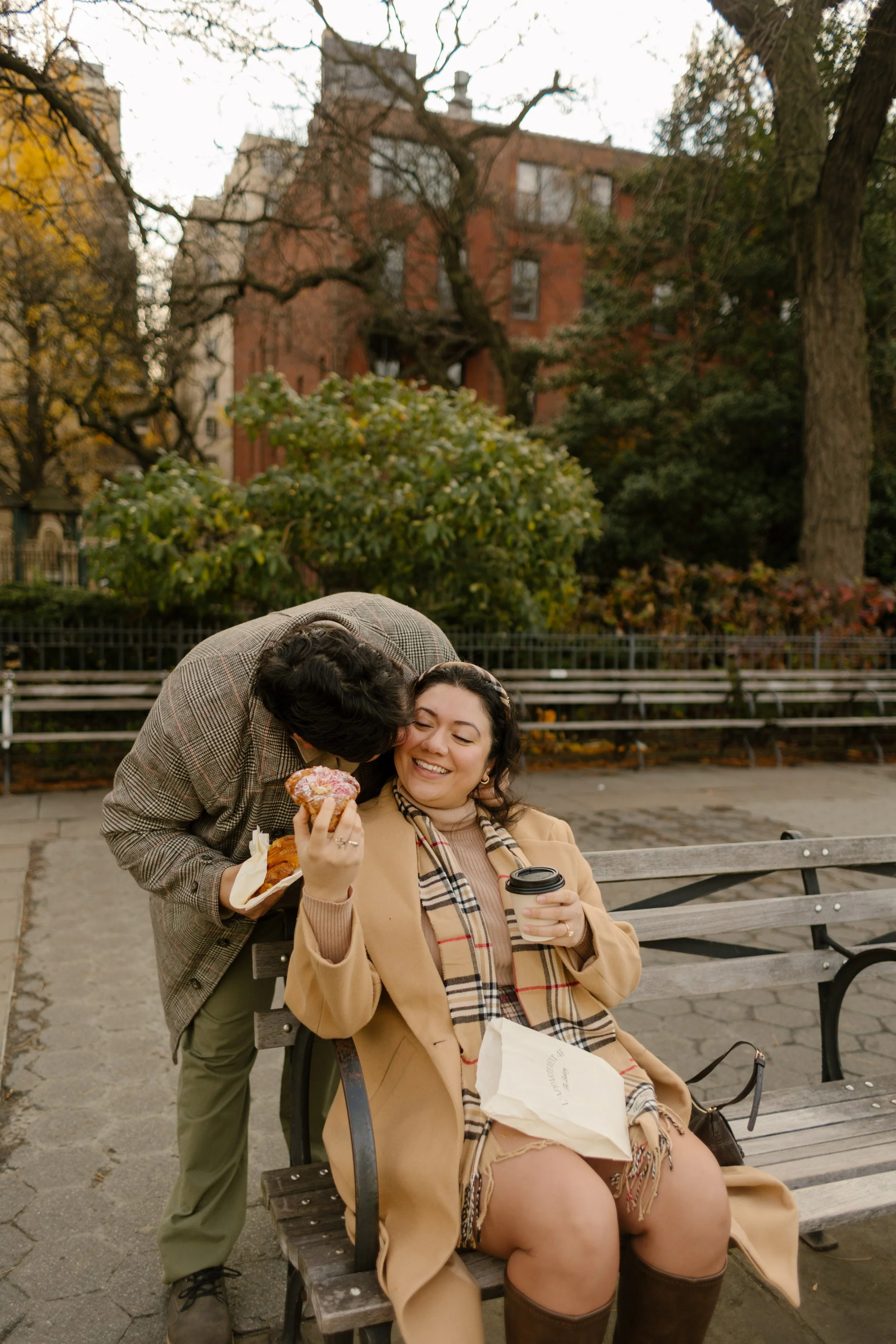 Couple share a playful moment on a park bench during an autumn New York City engagement session.