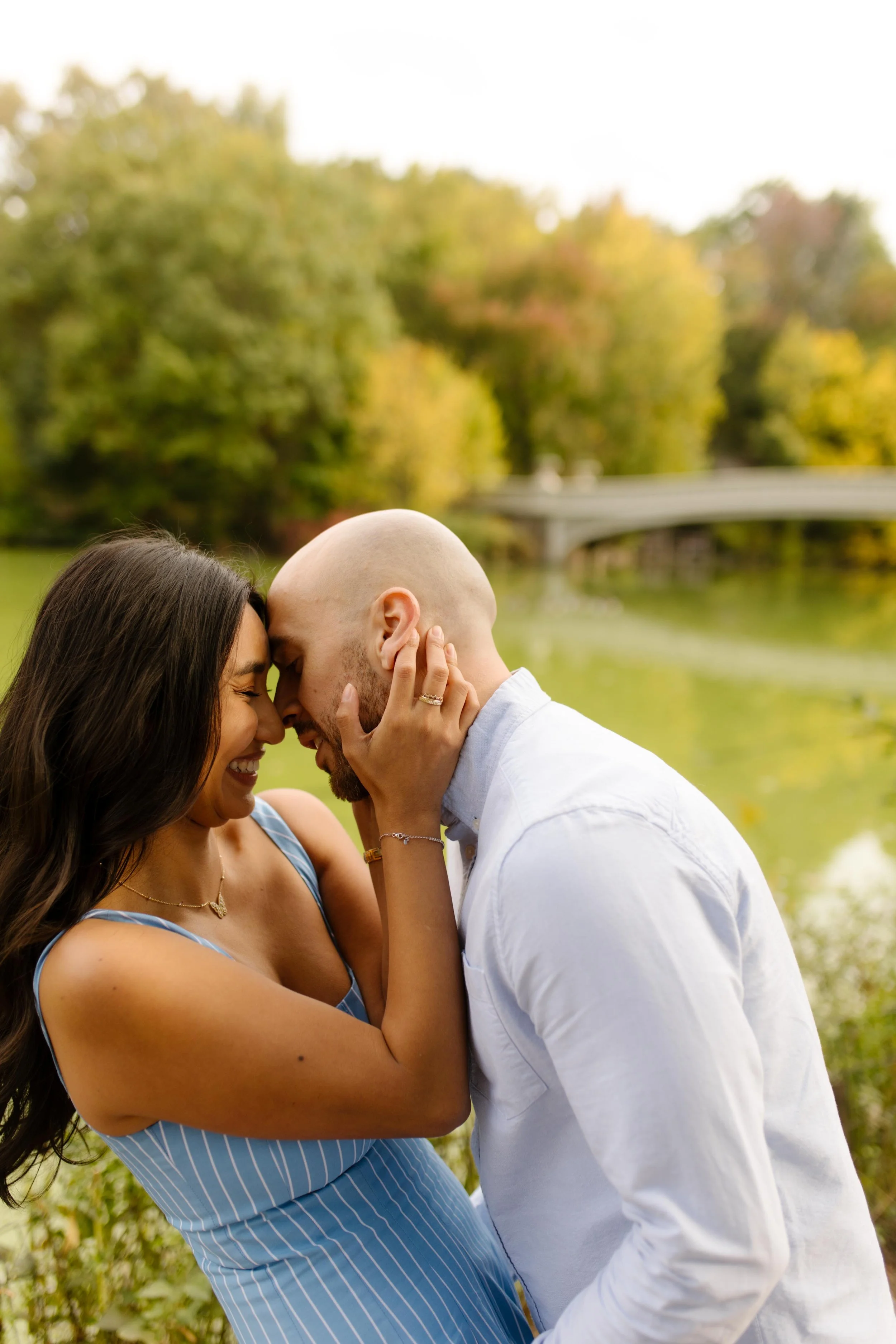 Couple share an affectionate moment beside a pond surrounded by greenery at one of the romantic wedding locations in New York.