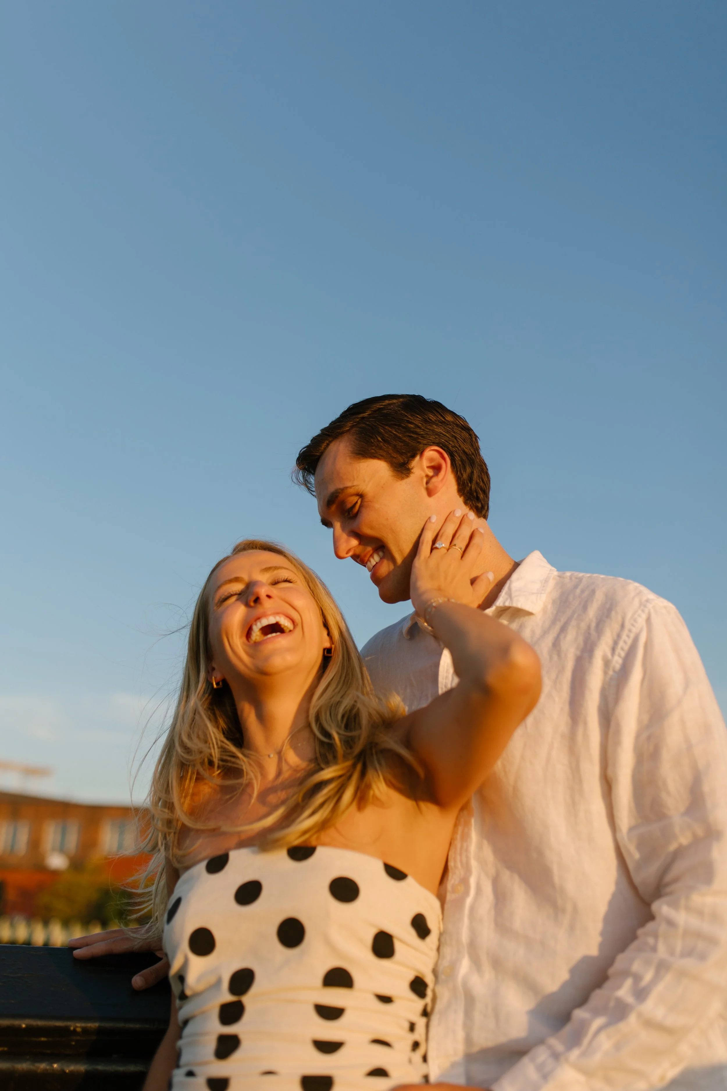 Laughing couple embrace by the water at sunset, capturing the relaxed atmosphere of wedding locations in New York.