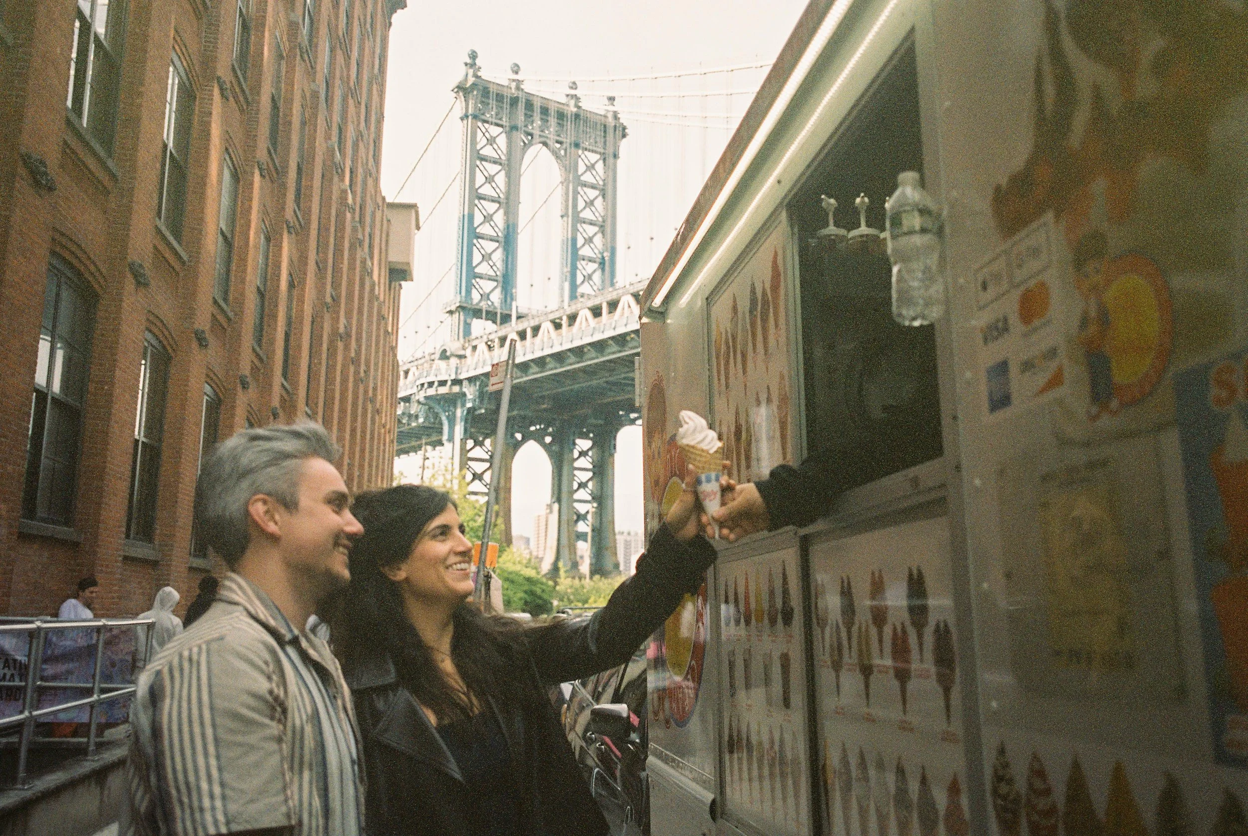 Couple enjoy ice cream near the Manhattan Bridge, highlighting the playful possibilities of wedding locations in New York.