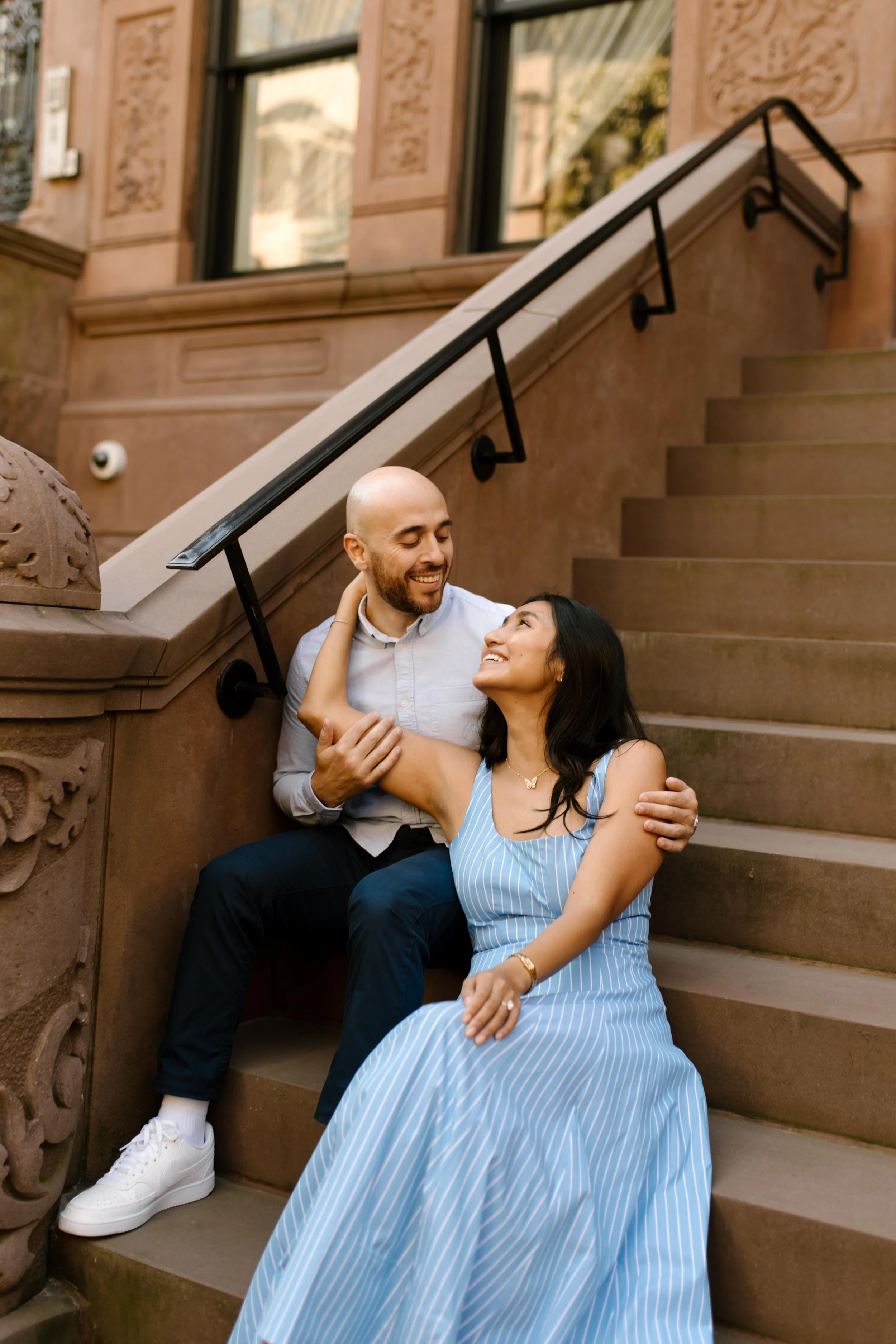 Couple sit together on a classic brownstone stoop, capturing the intimate charm of wedding locations in New York.