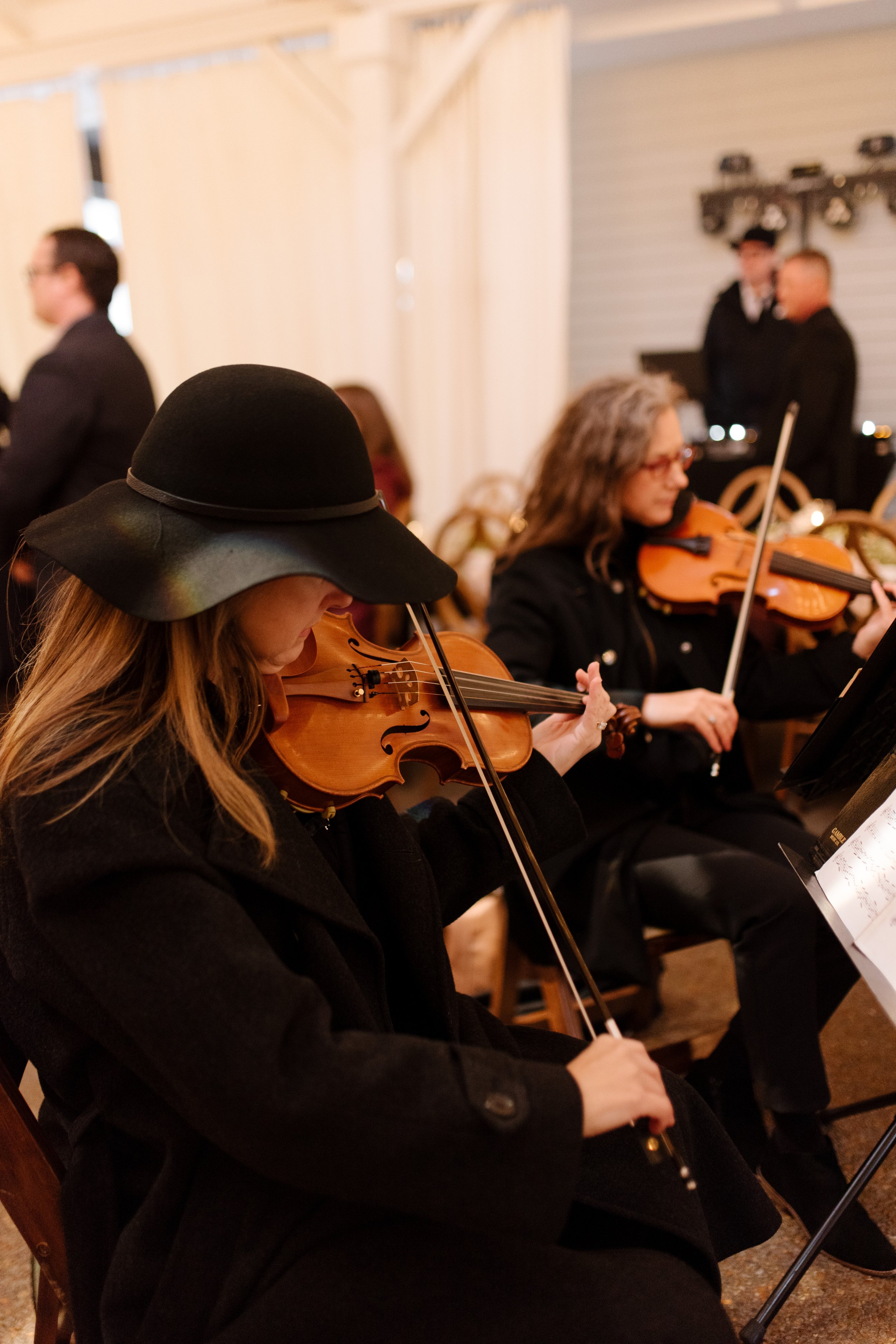 Live string musicians playing violins during an intimate fall wedding reception.
