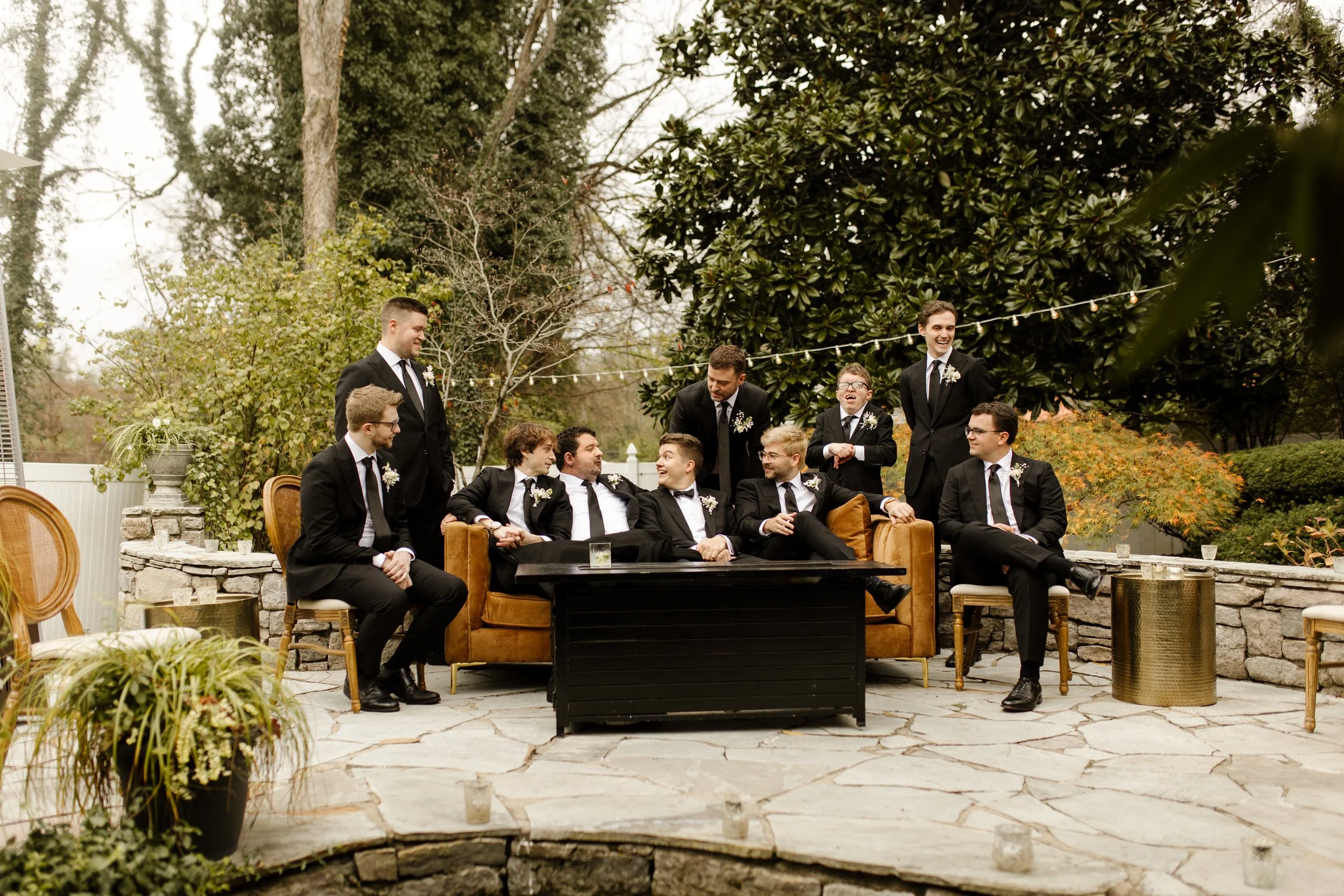 Groom and groomsmen relaxing together on an outdoor patio before the fall wedding ceremony.