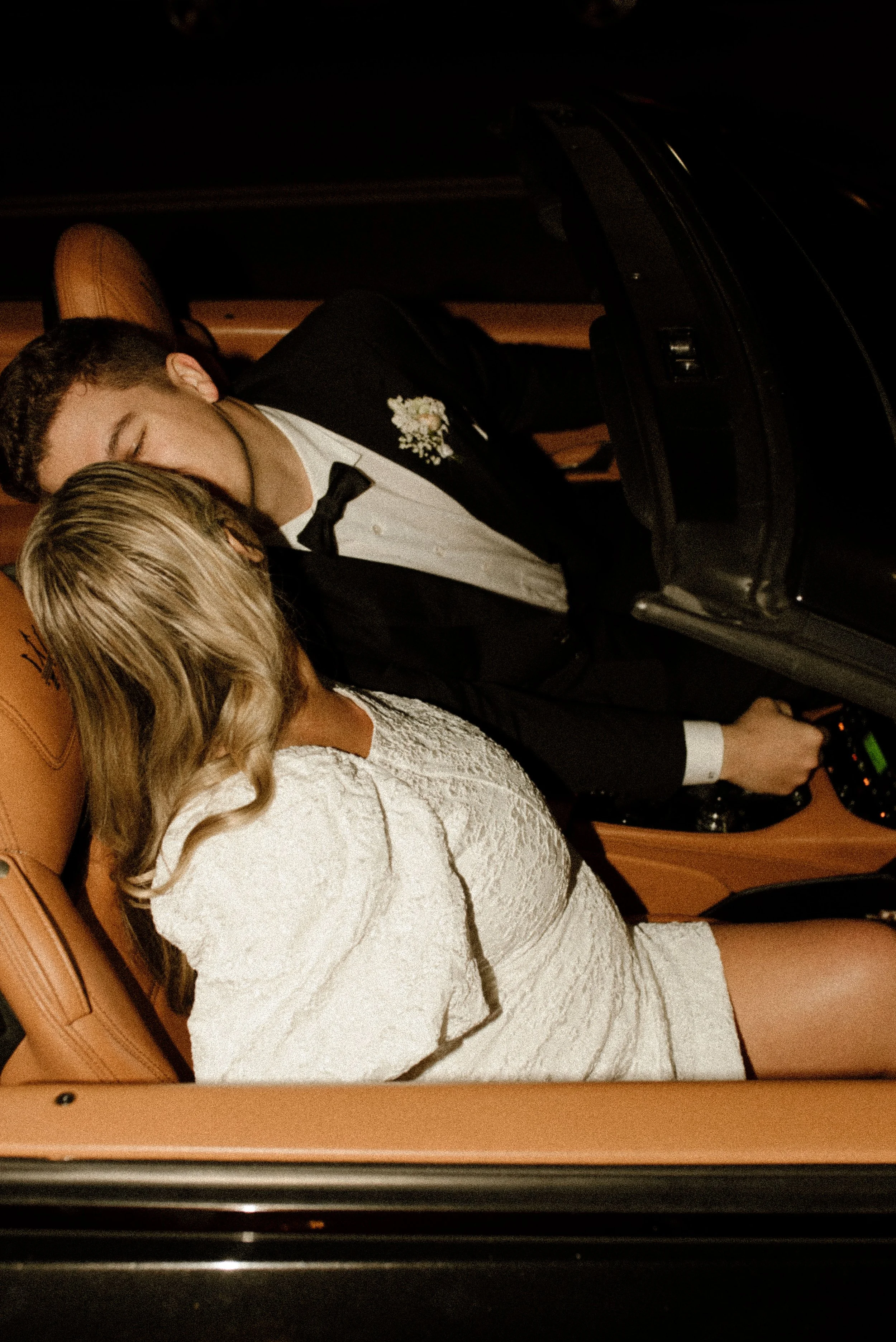 Newlyweds kissing inside a car at the end of their romantic fall wedding celebration.