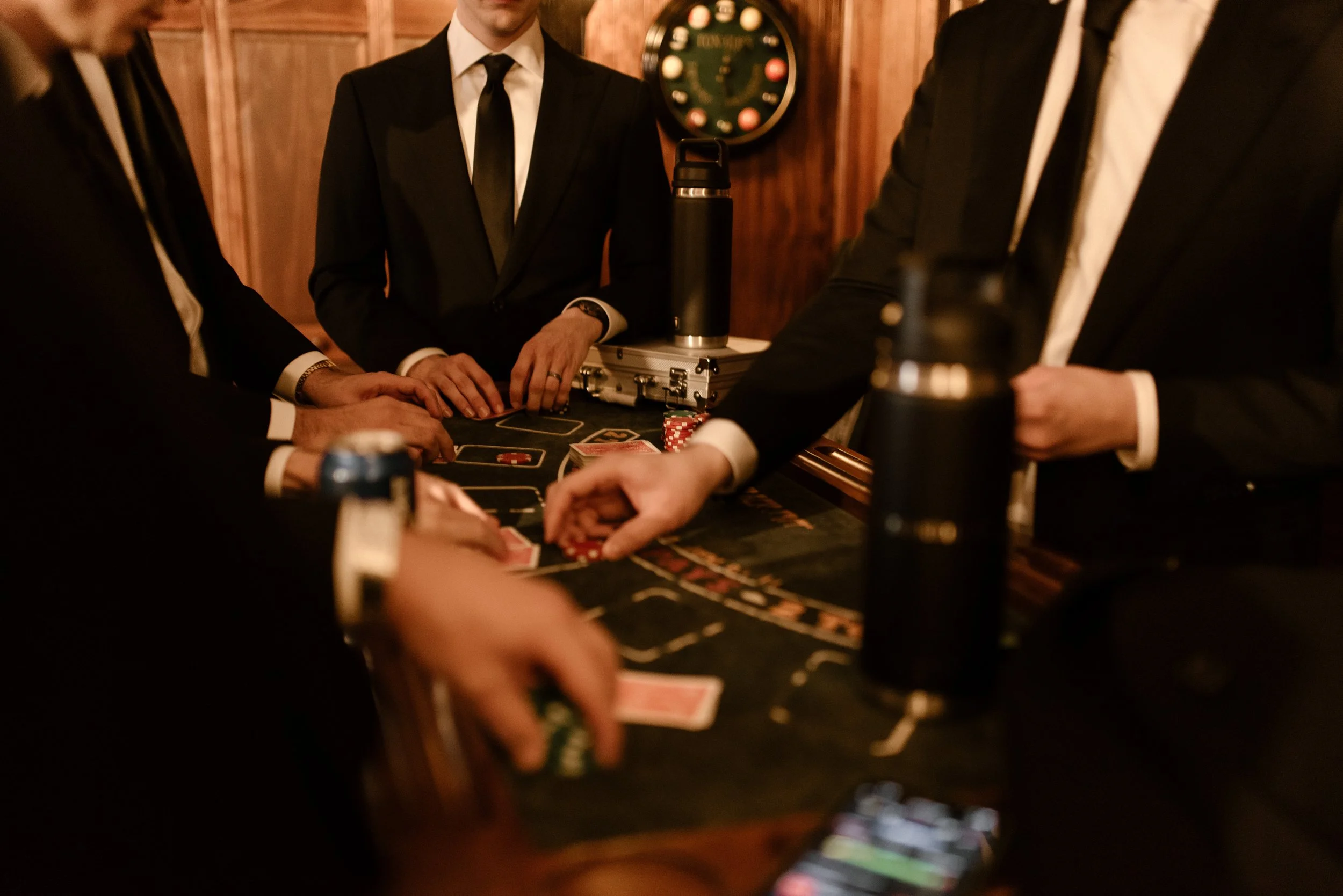 Wedding guests in black suits playing casino table games during a festive fall wedding reception.