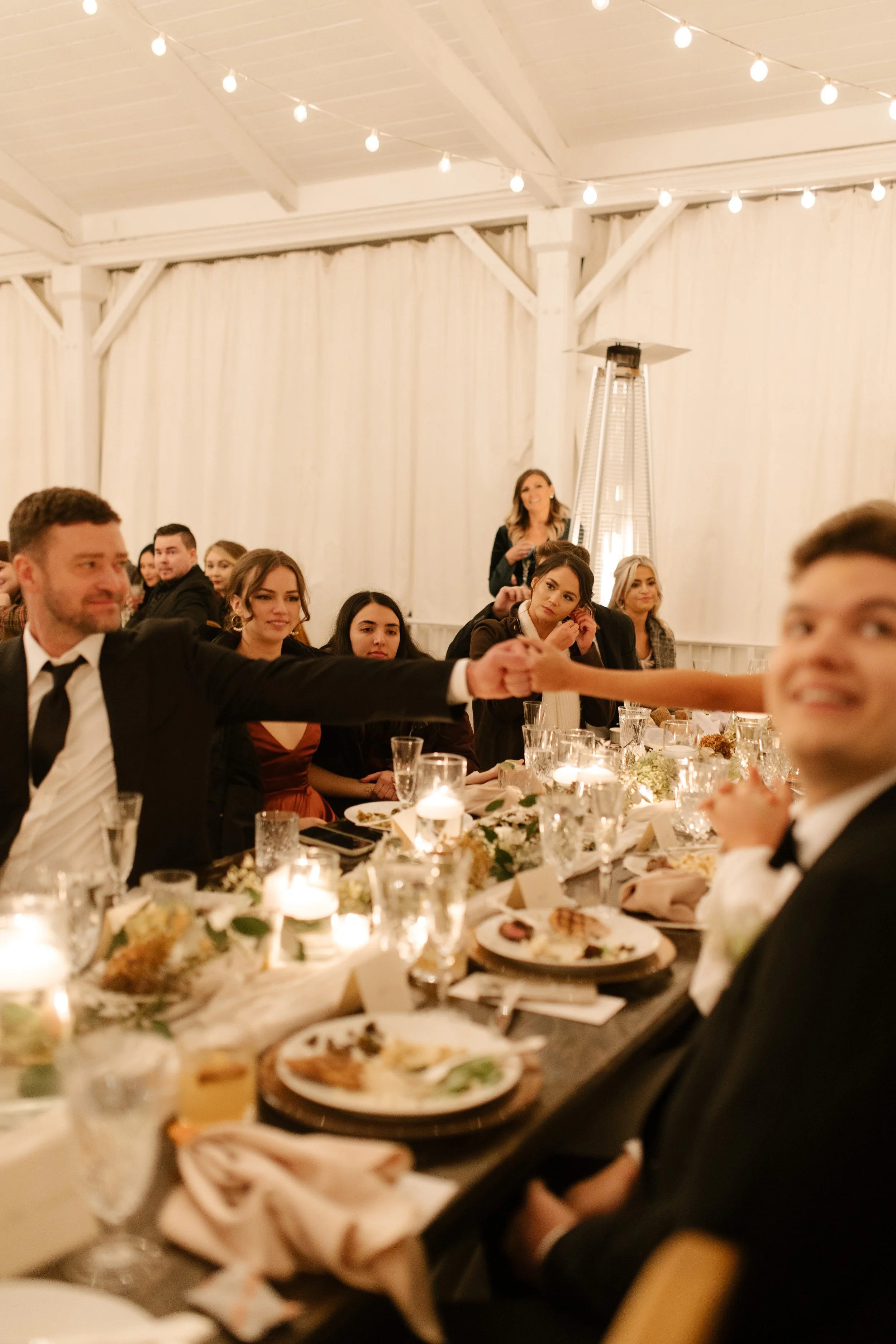 Wedding guests seated around a candlelit reception table during an elegant fall wedding dinner.
