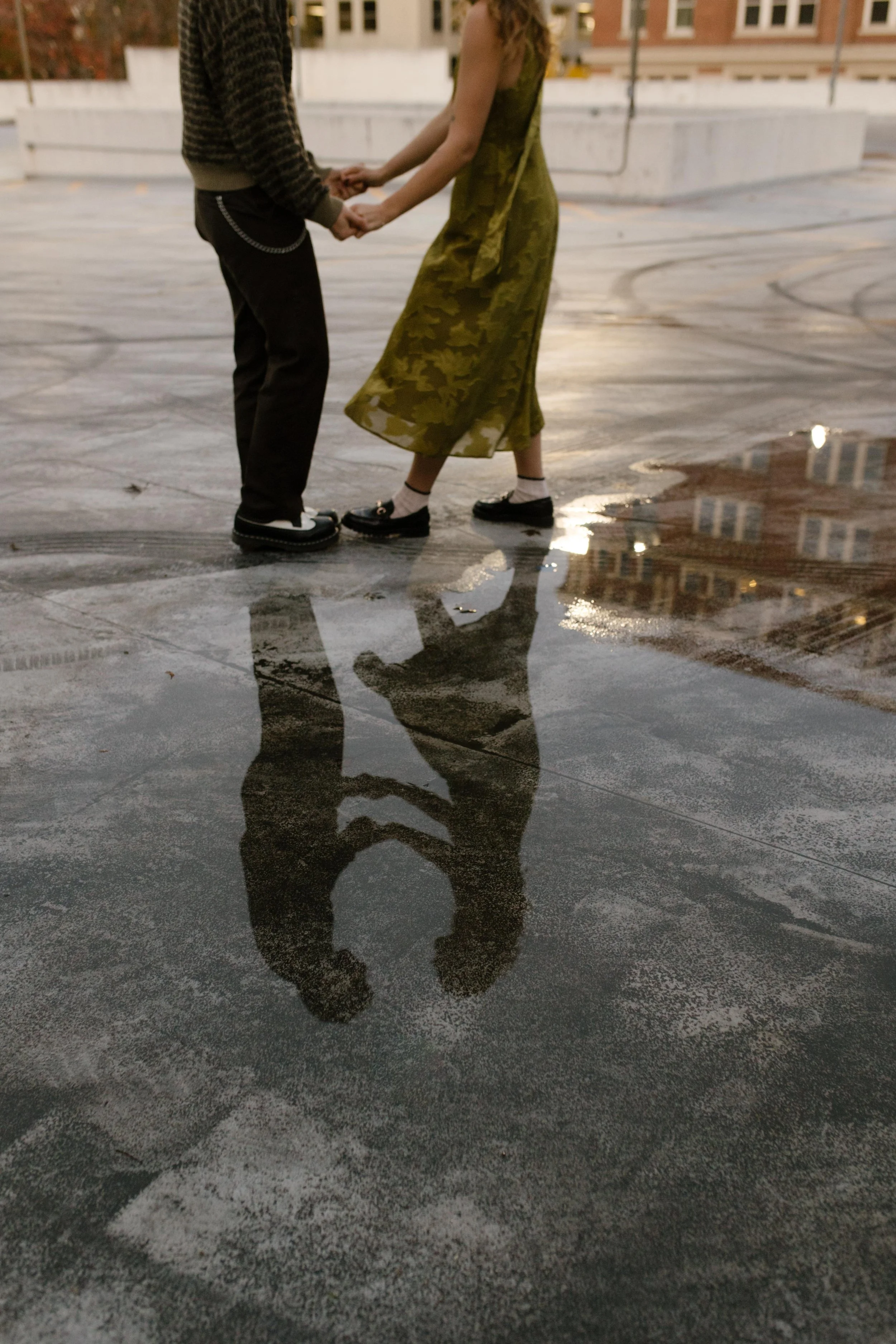 1. Artistic reflection of an engaged couple holding hands beside a rooftop puddle.