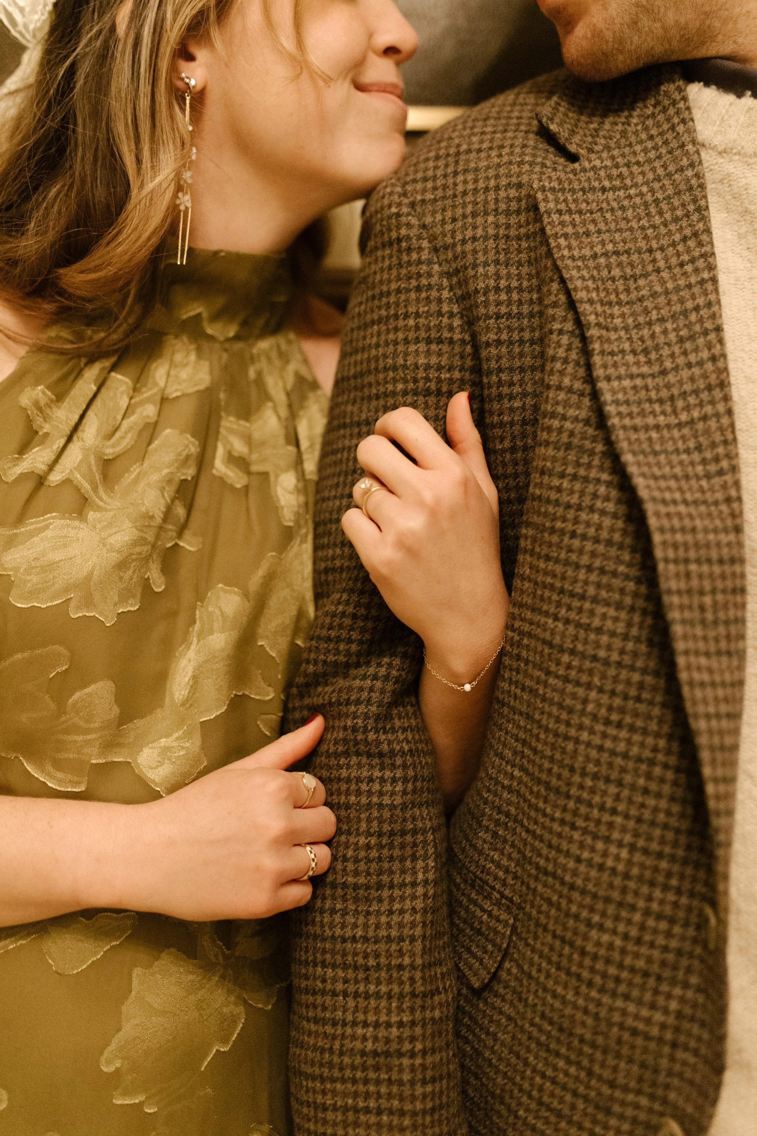 1. Close-up portrait of an engaged woman holding her partner’s blazer, with her engagement ring visible.