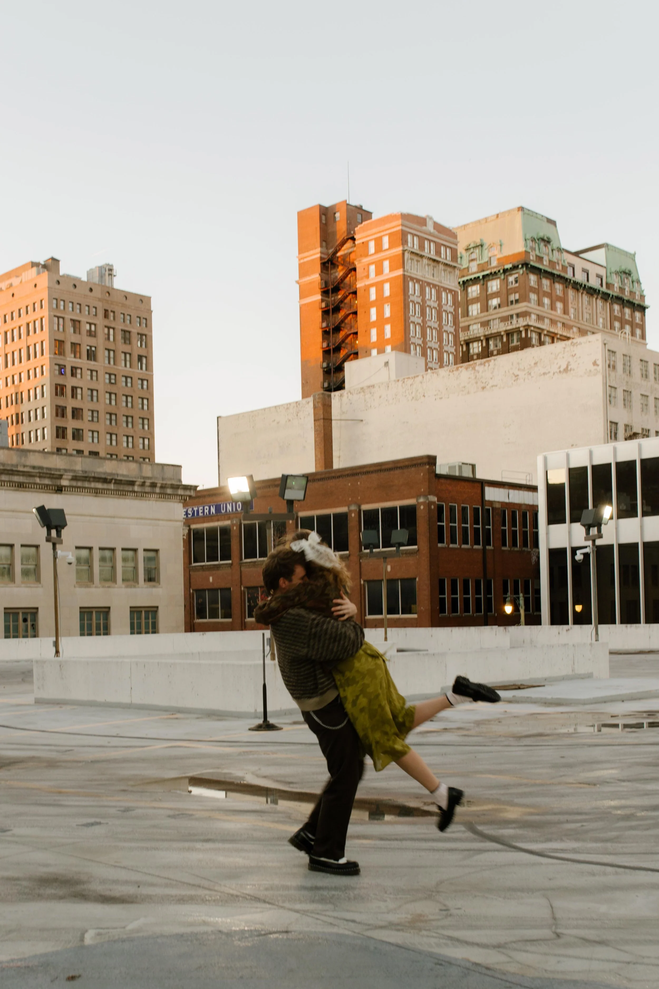 Couple spinning and embracing on a rooftop during engagement photos in NYC, with downtown buildings in the background.