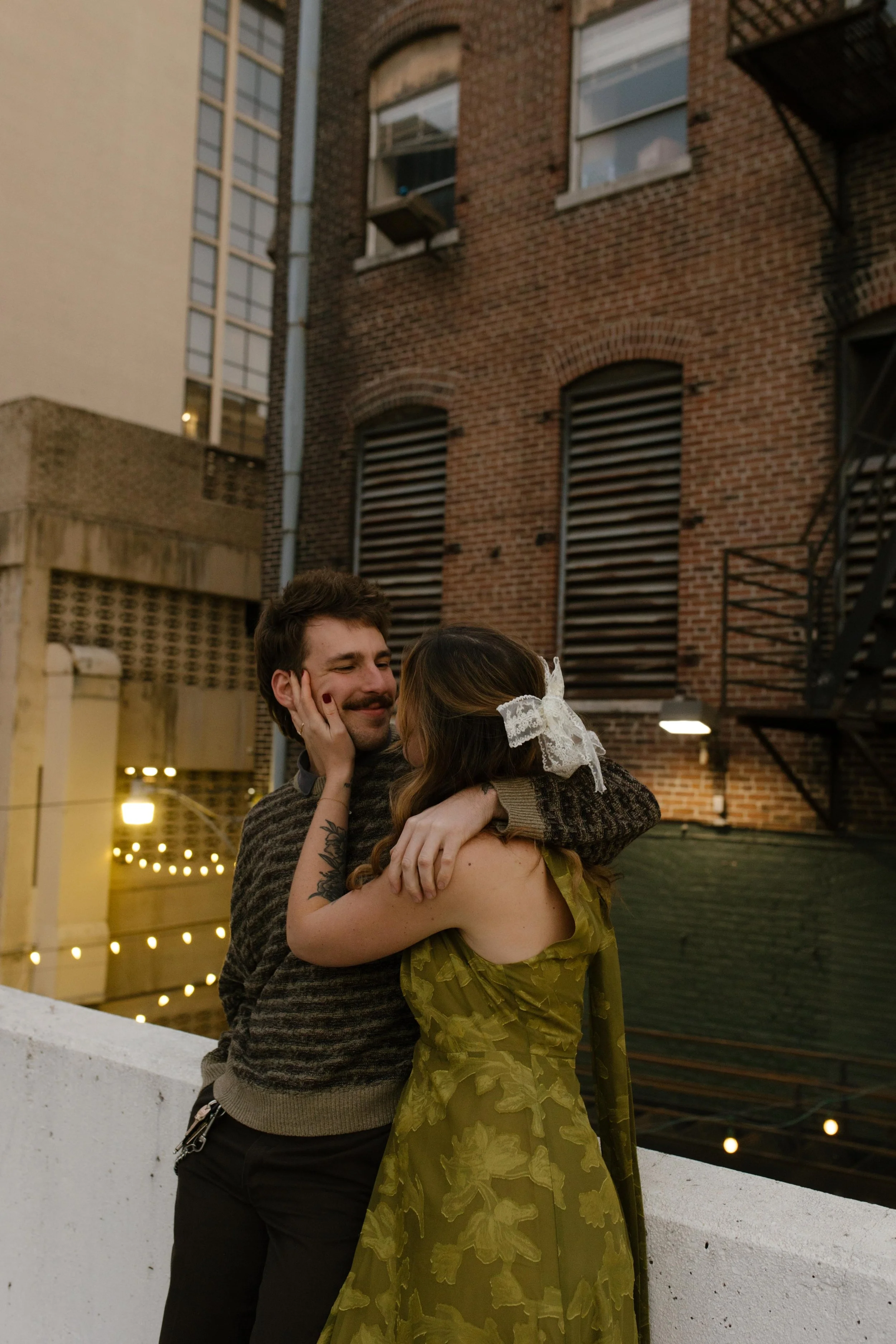 Couple embracing beside a brick building and fire escape during engagement photos in NYC.