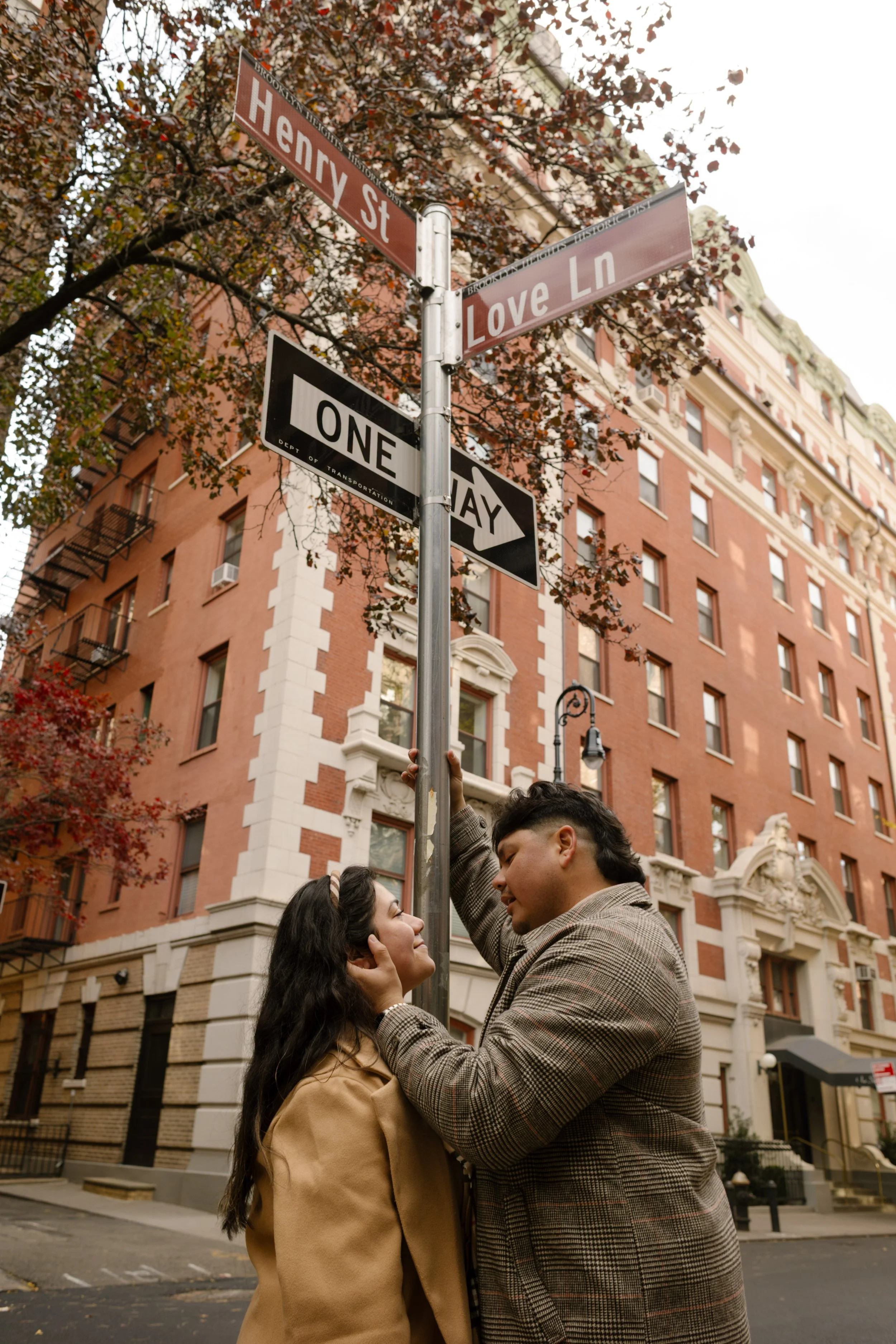 Romantic fall engagement portrait beneath the Love Lane street sign on a quiet Brooklyn Heights street.