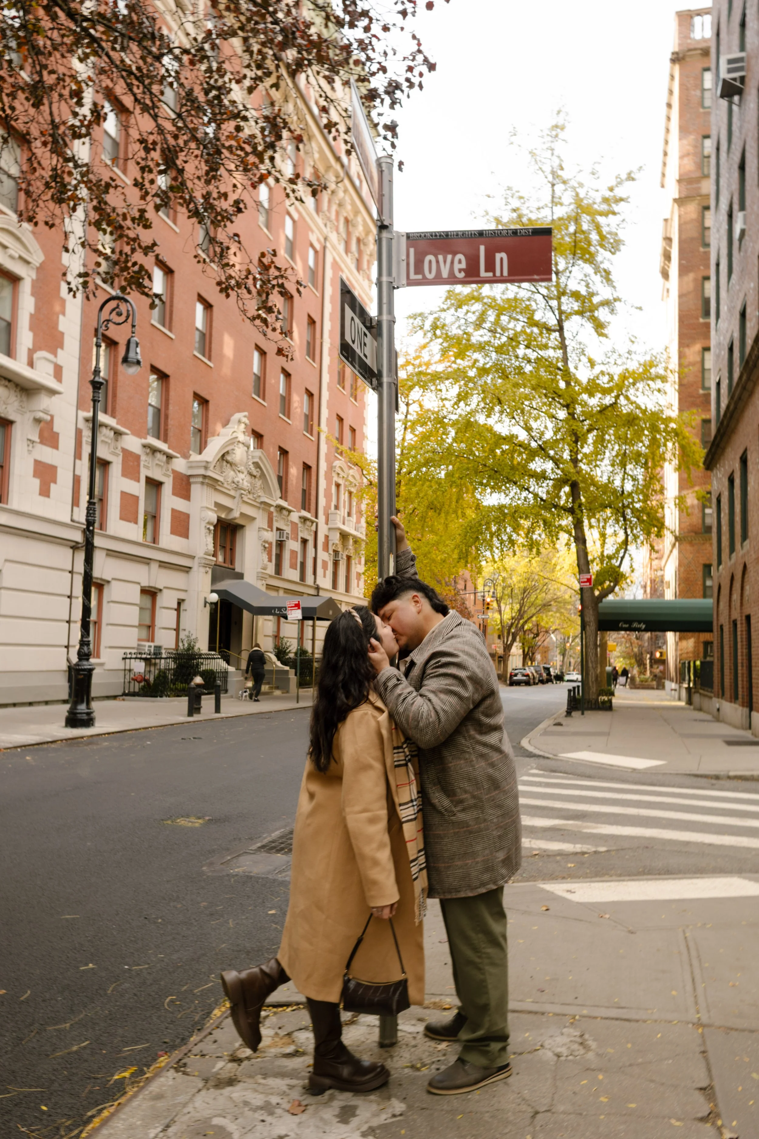 1. Brooklyn engagement photos of a couple kissing beneath a Love Ln street sign during a romantic fall session in Brooklyn Heights.