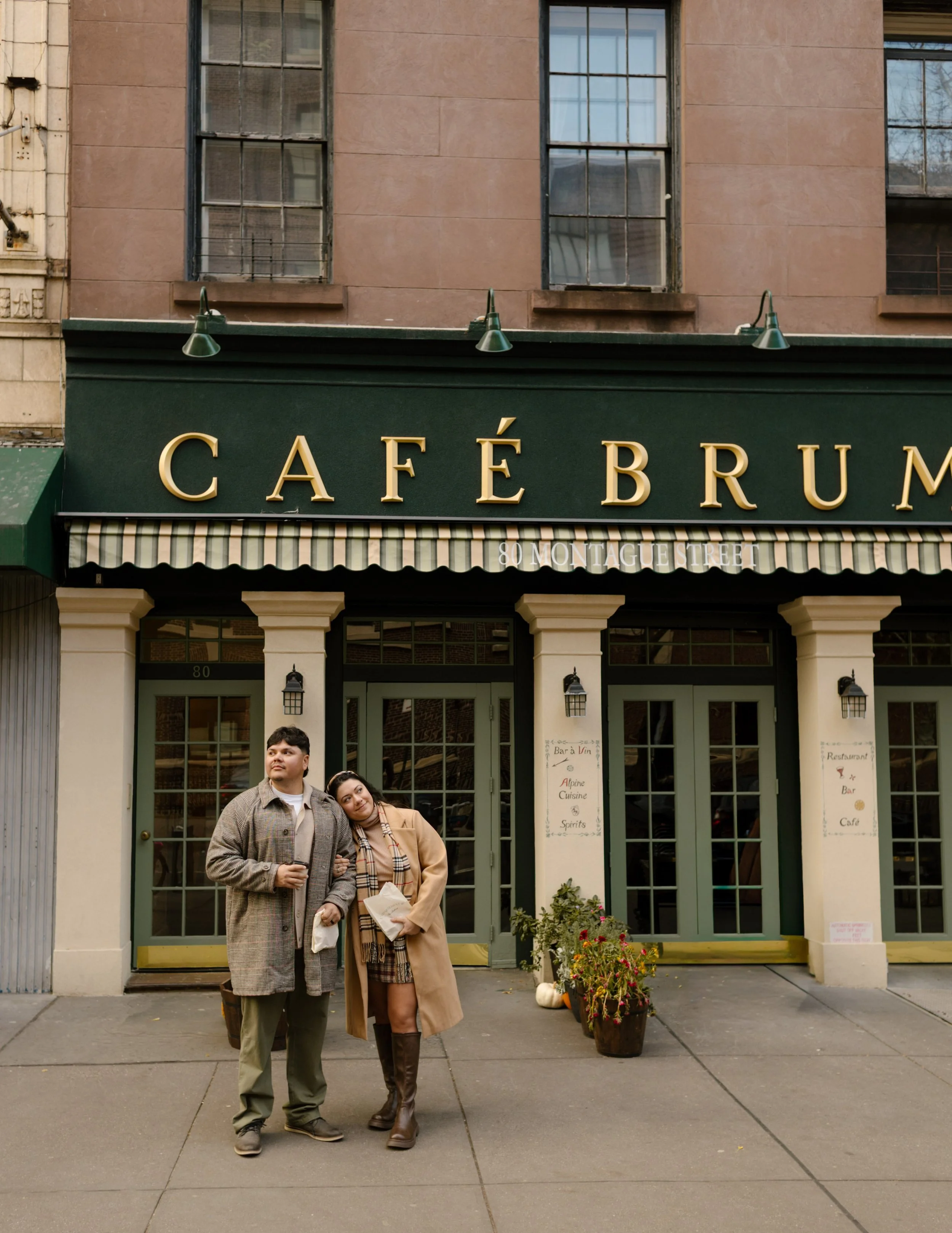Brooklyn engagement photos of a couple outside Café Brume holding pastries and coffee during a cozy fall date.